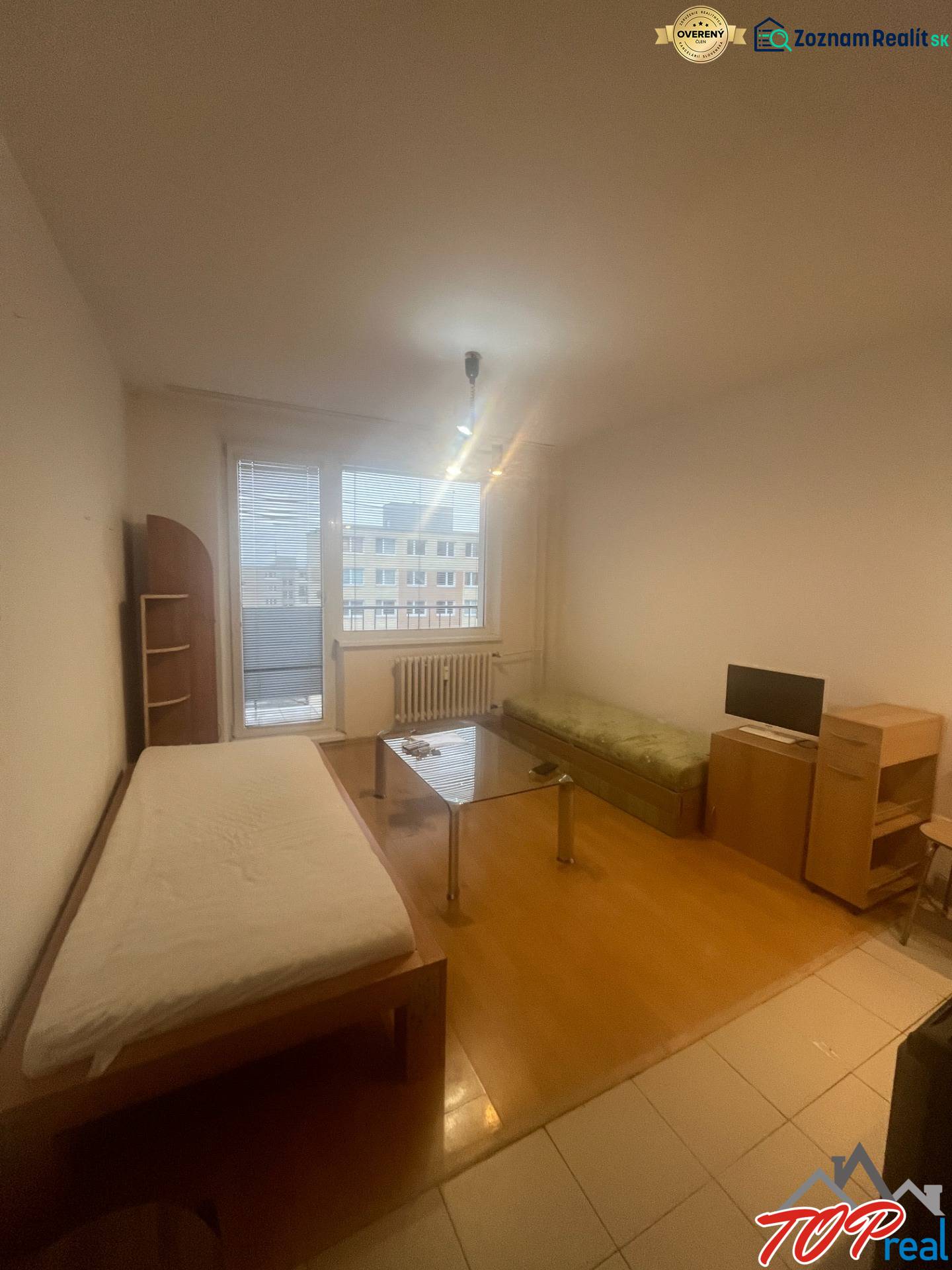 Einzimmerwohnung mit Holzboden, Bett, Sofa und Tisch, einfaches Interieur.