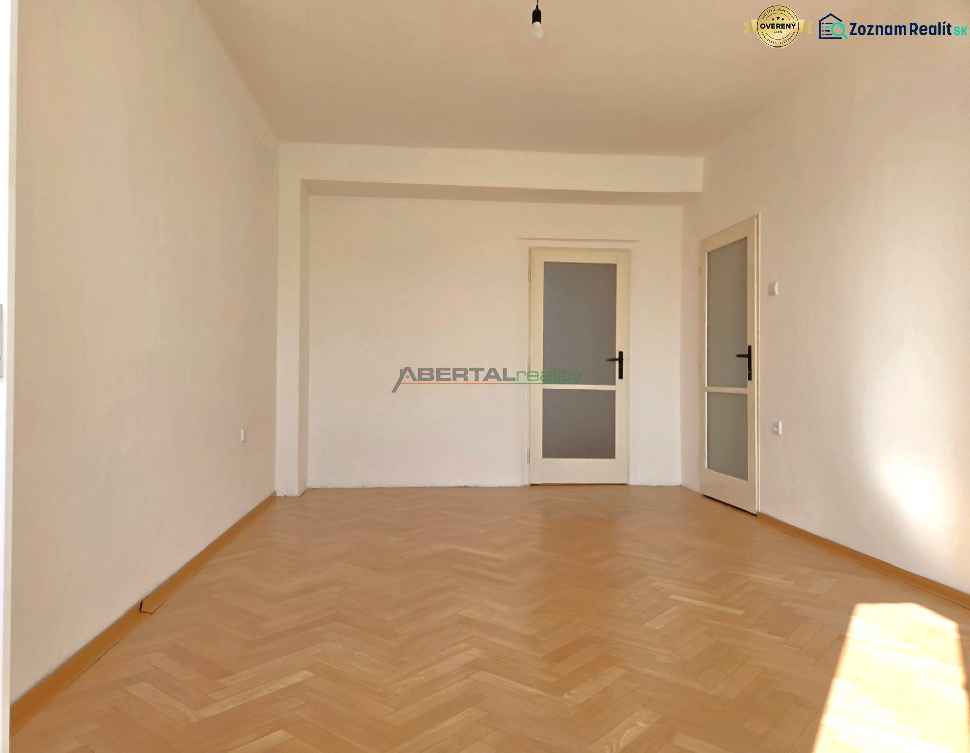 Ein Zimmer in der 3-Zimmer-Wohnung hat einen Boden mit Holzdekor und weiße Wände.