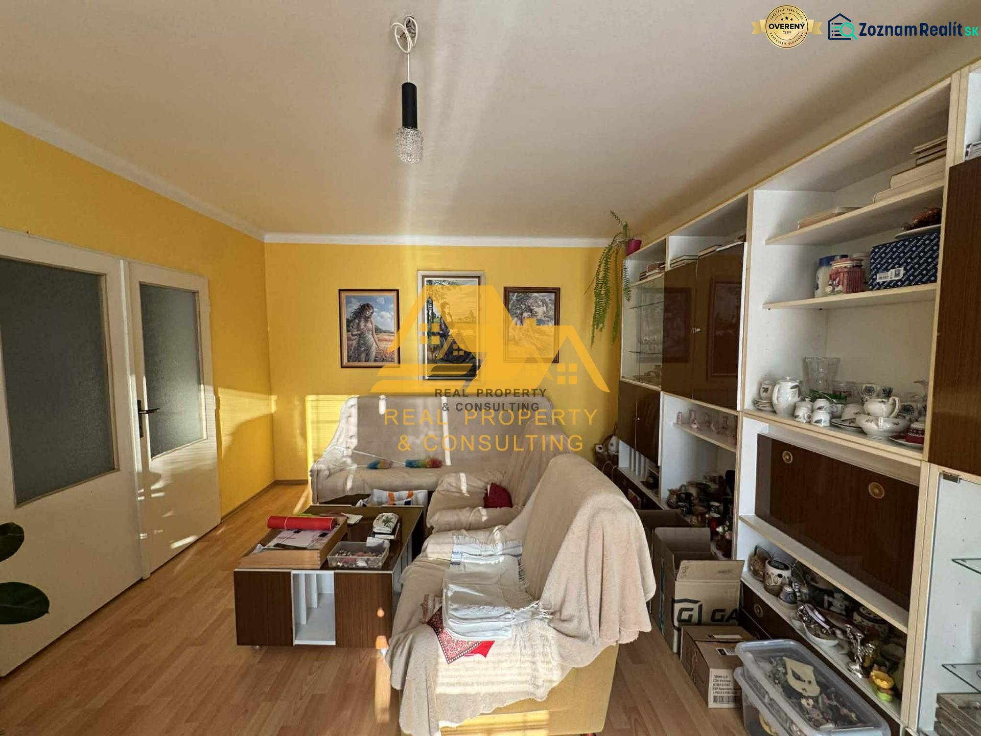 Wohnzimmer in einem Einfamilienhaus mit weißem Sofa, Holzboden, gelbe Wände.