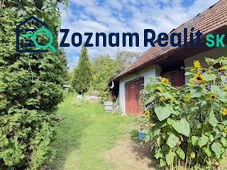 Ein Einfamilienhaus in Krivosúd-Bodovka mit roten Türen und Sonnenblumen im Garten.