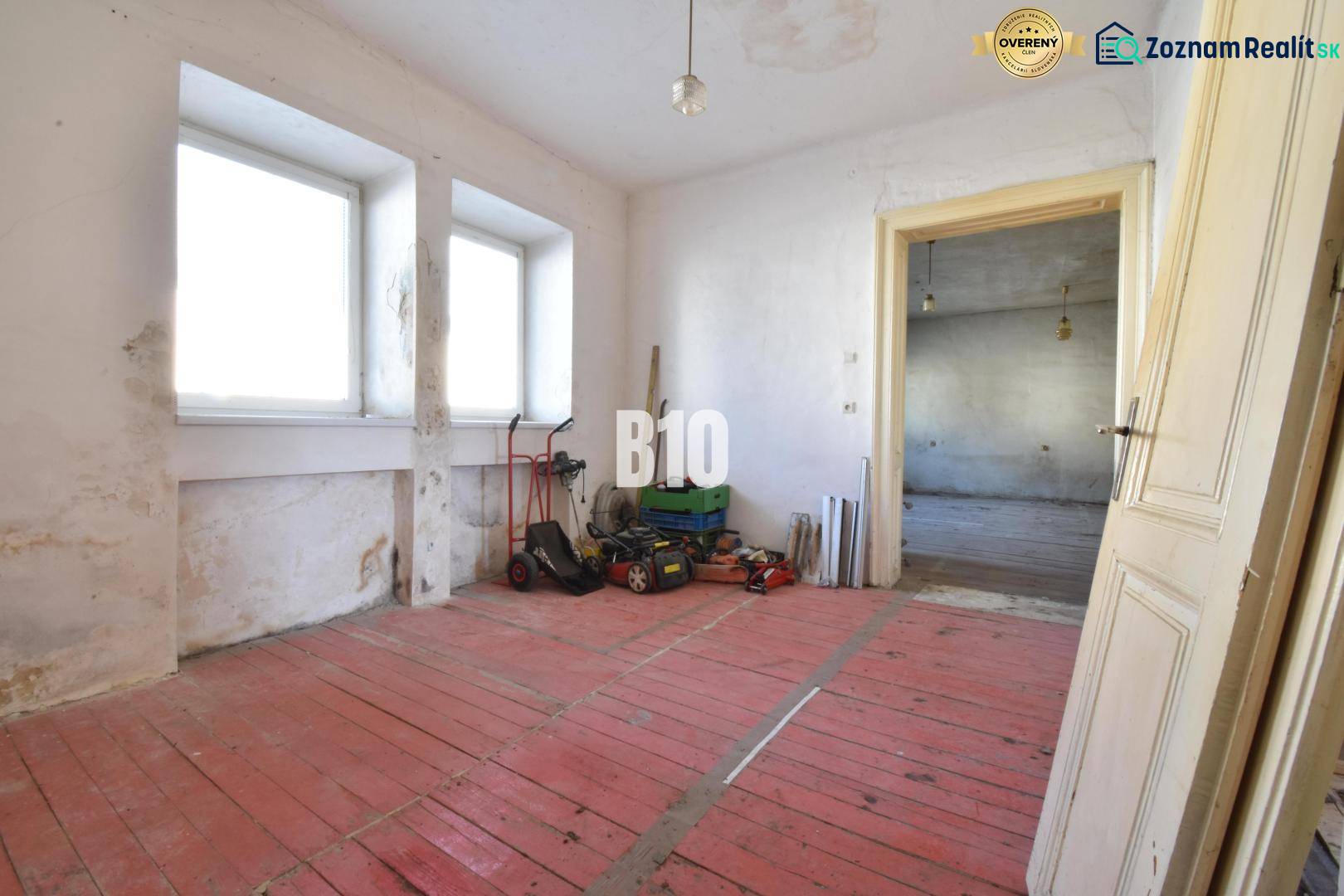 Ein Zimmer in einem Einfamilienhaus mit rotem Boden und Fenstern, Bytča.