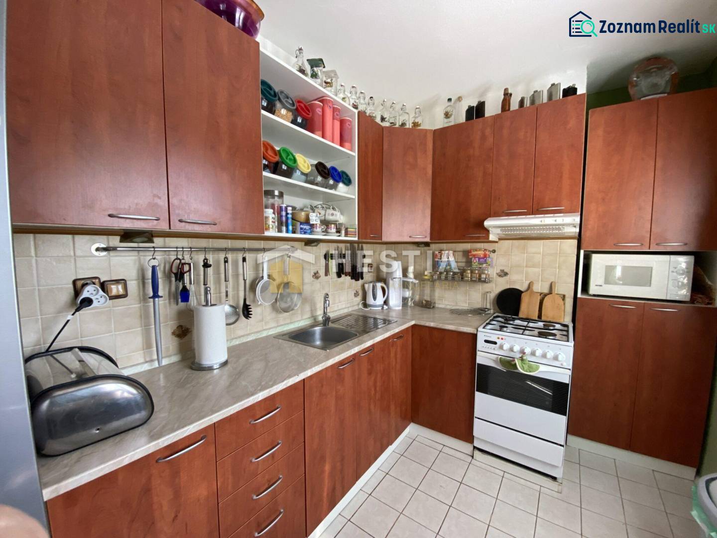 Küche in einer 2-Zimmer-Wohnung mit Holzschränken und weißen Fliesen.