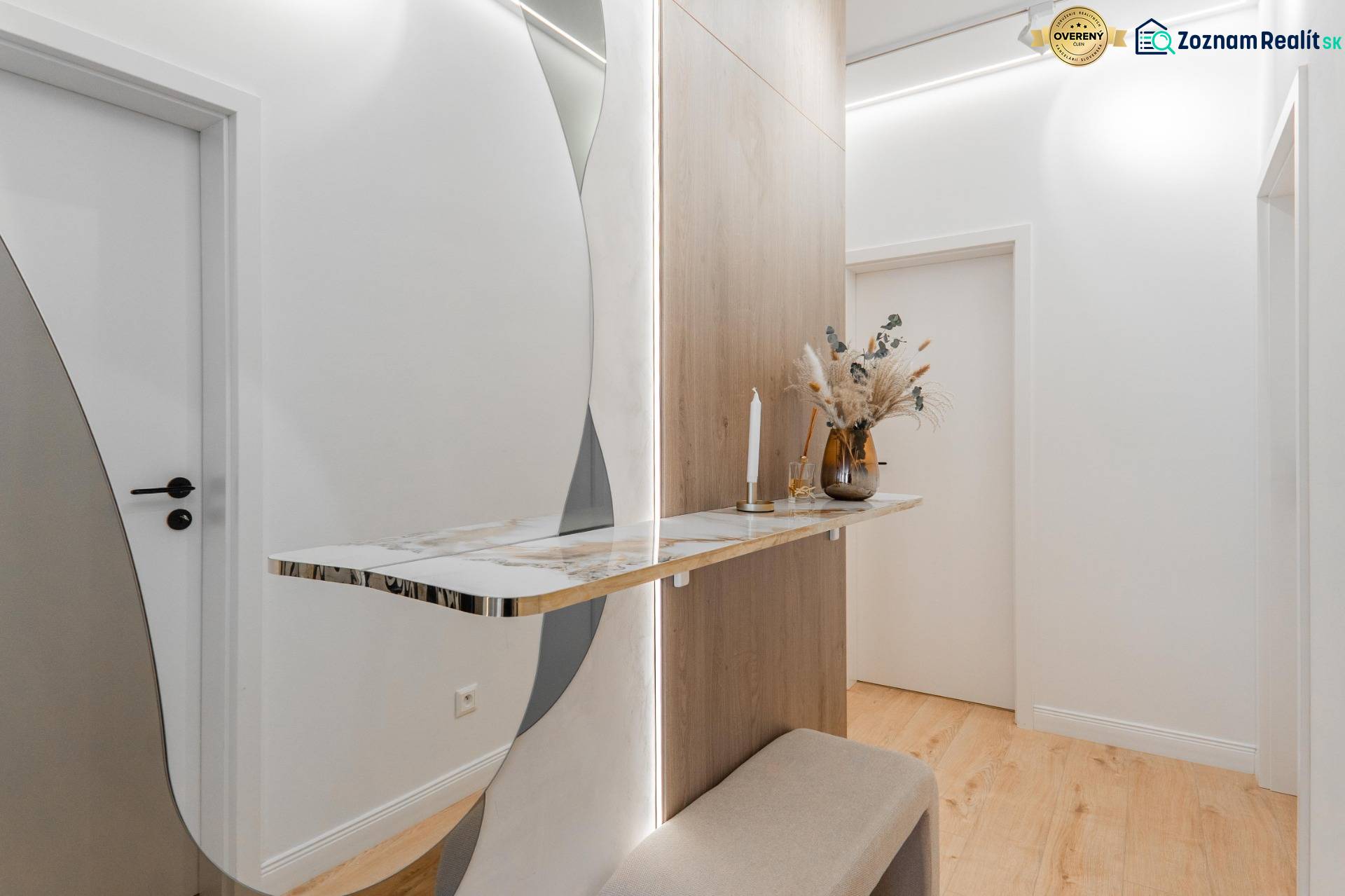 Flur in einer 3-Zimmer-Wohnung mit einem minimalistischen Tisch, einem Spiegel und einem Boden mit Holzdekor.