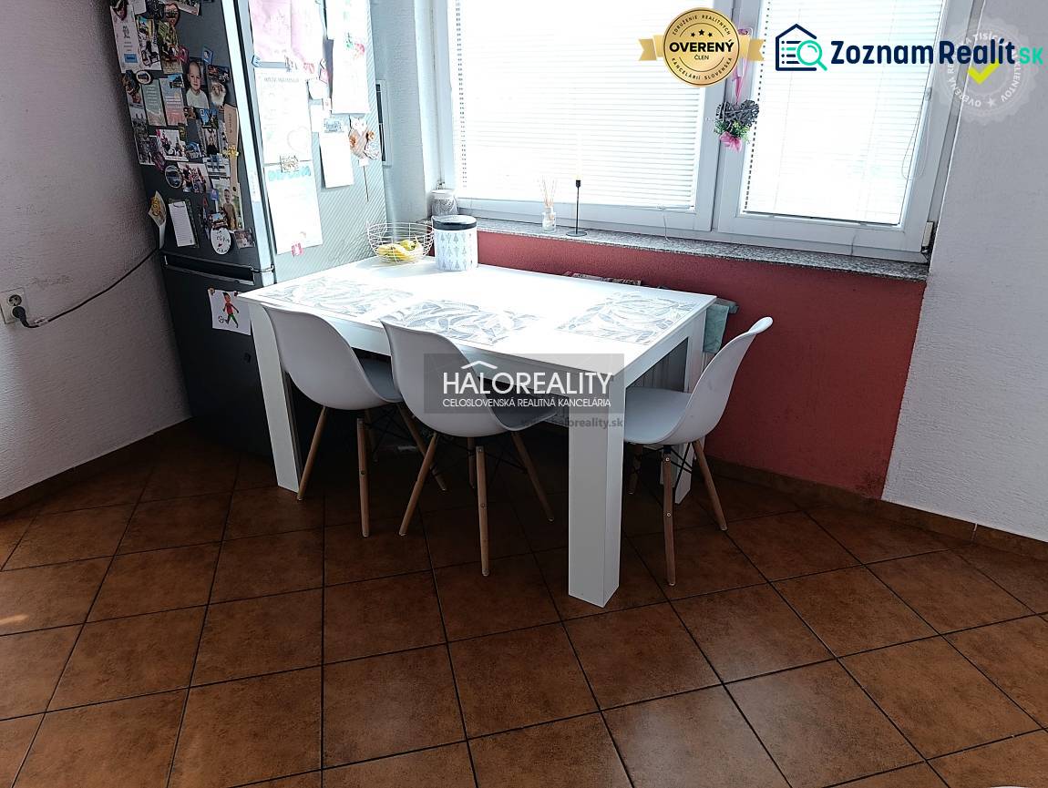 Küche einer 2-Zimmer-Wohnung mit Esstisch, weißen Stühlen und Fenster.