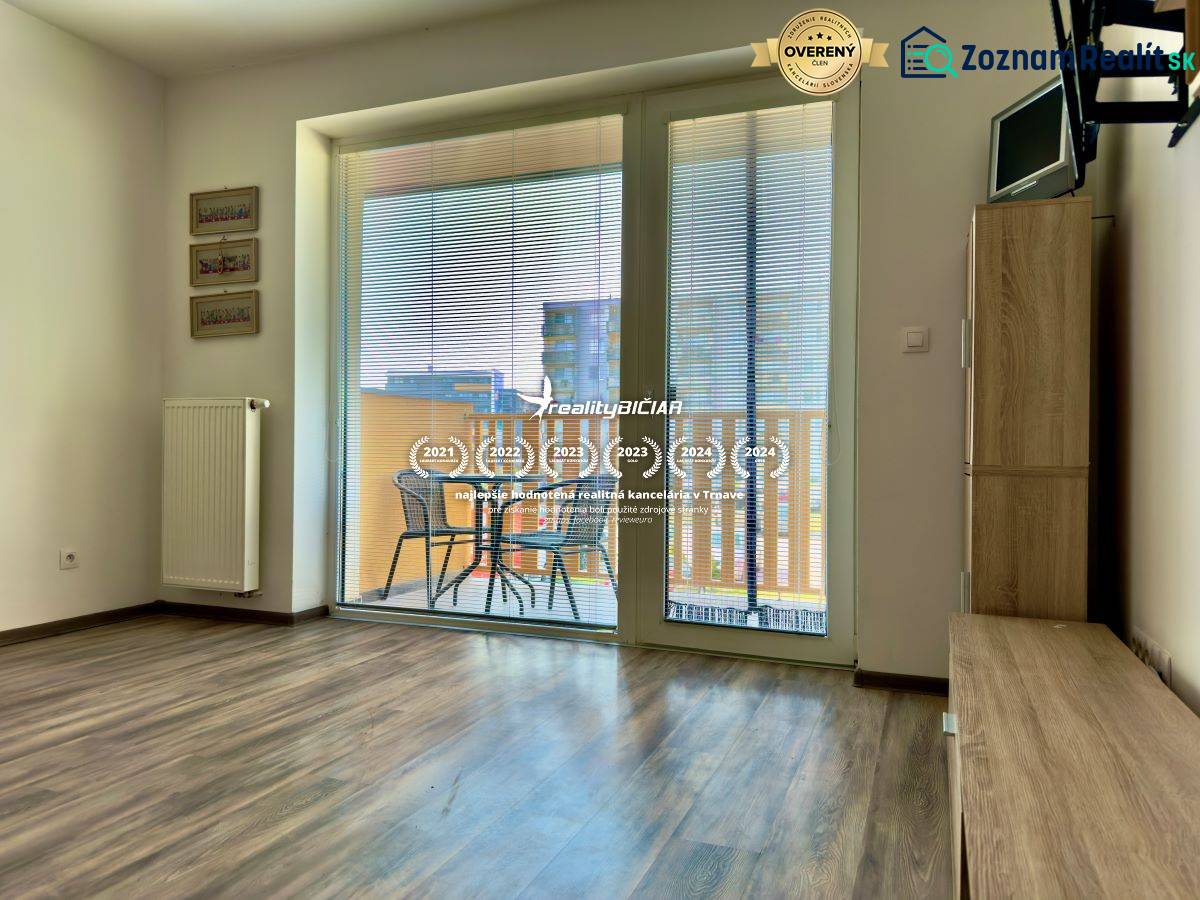 Wohnzimmer in einer 2-Zimmer-Wohnung mit Holzboden und Zugang zum Balkon.