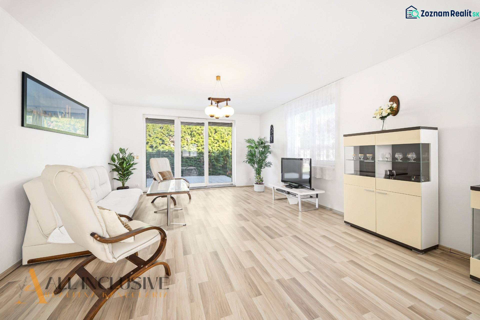 Helles Wohnzimmer mit Holzboden, Sofa, Sessel und Fernseher.