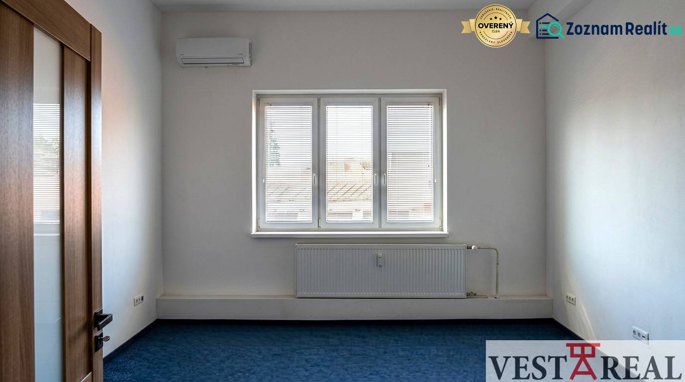 Ein Zimmer mit Klimaanlage und Fenster in Büros, blauer Teppichboden, weiße Wände.