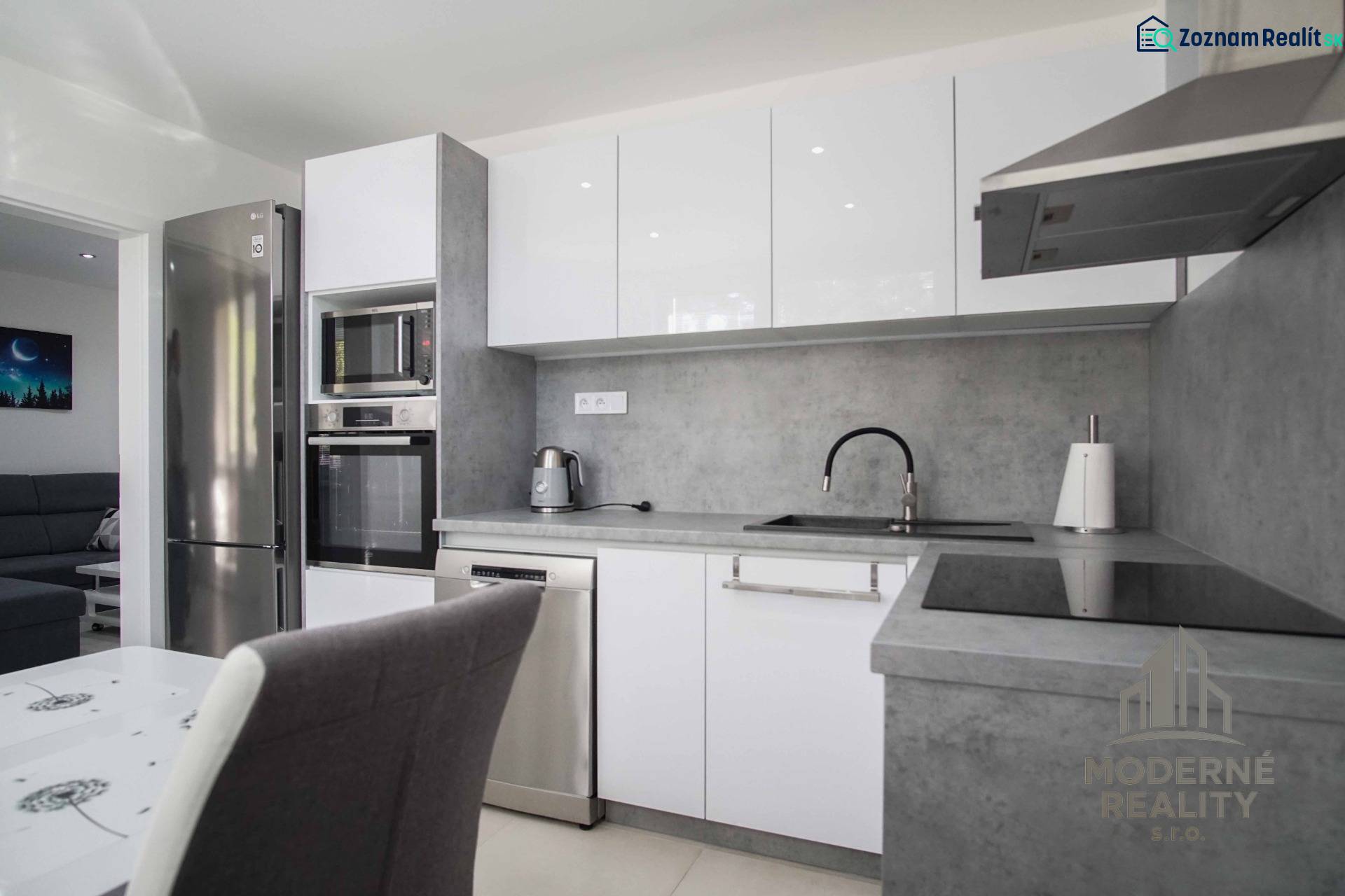 Küche in einer 2-Zimmer-Wohnung mit Edelstahlgeräten und grauer Arbeitsplatte.