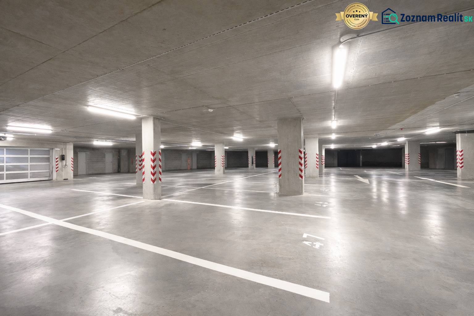 Geräumige Garagen mit markierten Parkplätzen, helle Beleuchtung, Betonpfeiler.