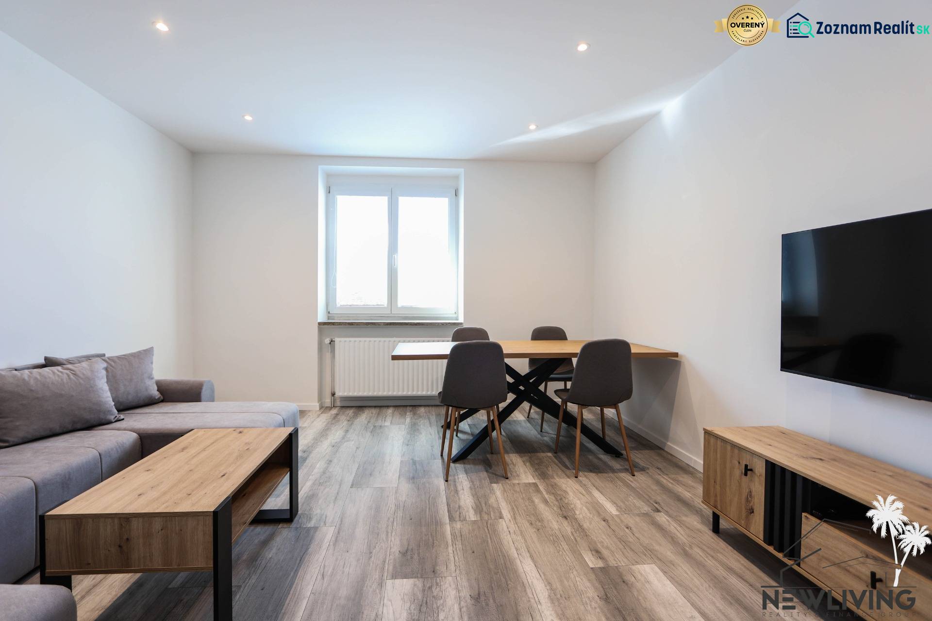 Wohnzimmer mit Holzboden, Sofa, Esstisch und Fernseher in einer 3-Zimmer-Wohnung.