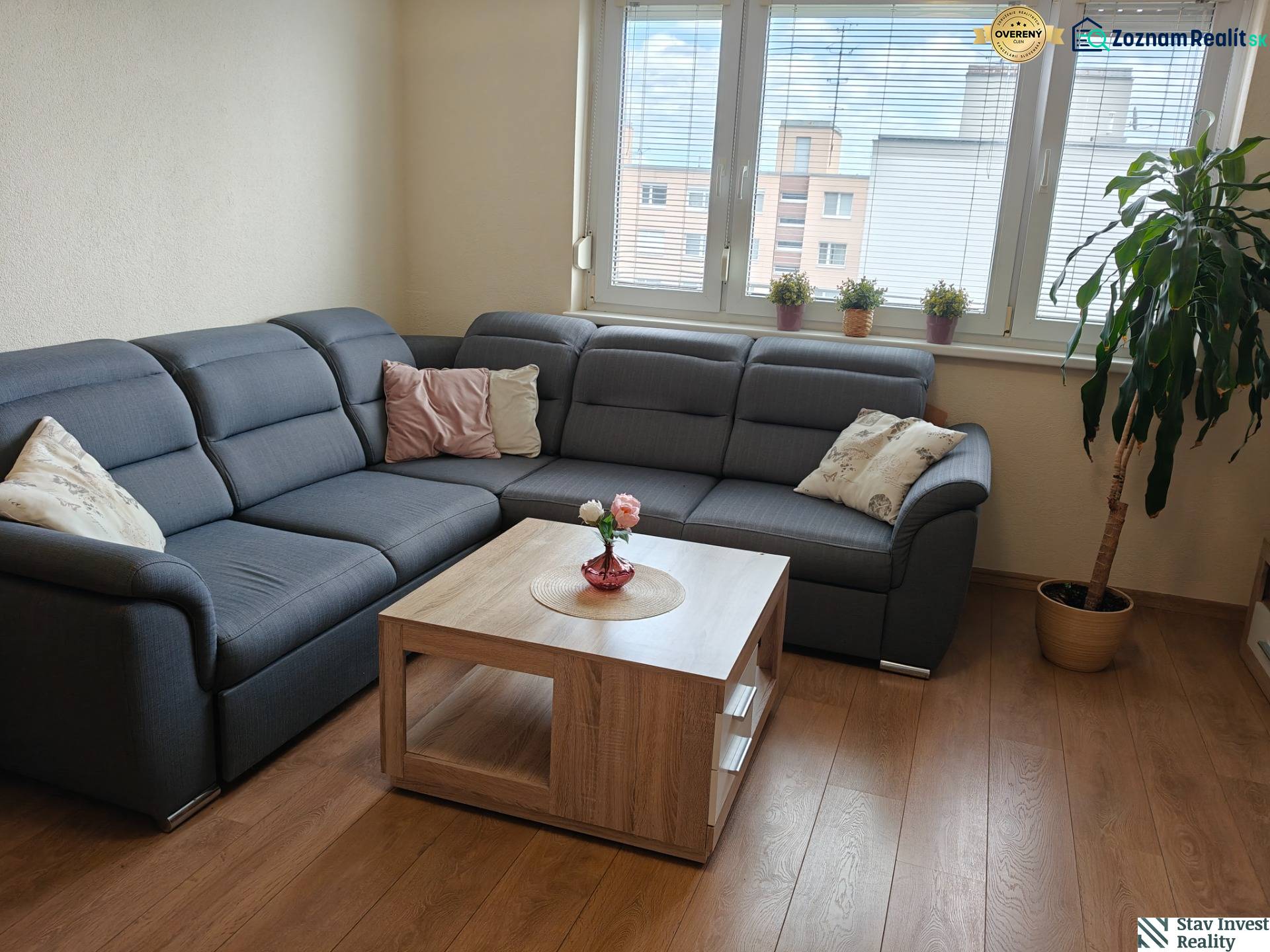 Wohnzimmer in einer 3-Zimmer-Wohnung mit Ecksofa und Boden in Holzoptik.