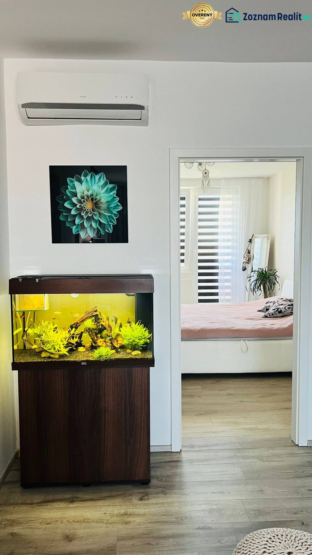 Ein Aquarium und ein Boden mit Holzdekor in einer 3-Zimmer-Wohnung, Übergang in ein helles Schlafzimmer.