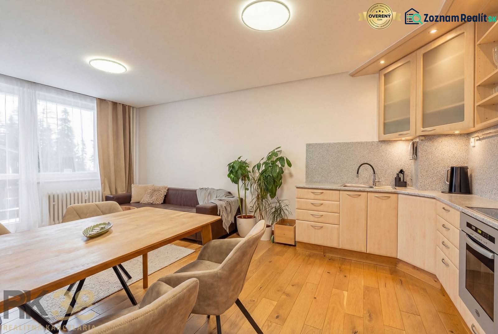 Innenraum einer Ferienwohnung mit Sofa, Küche und Holzboden.