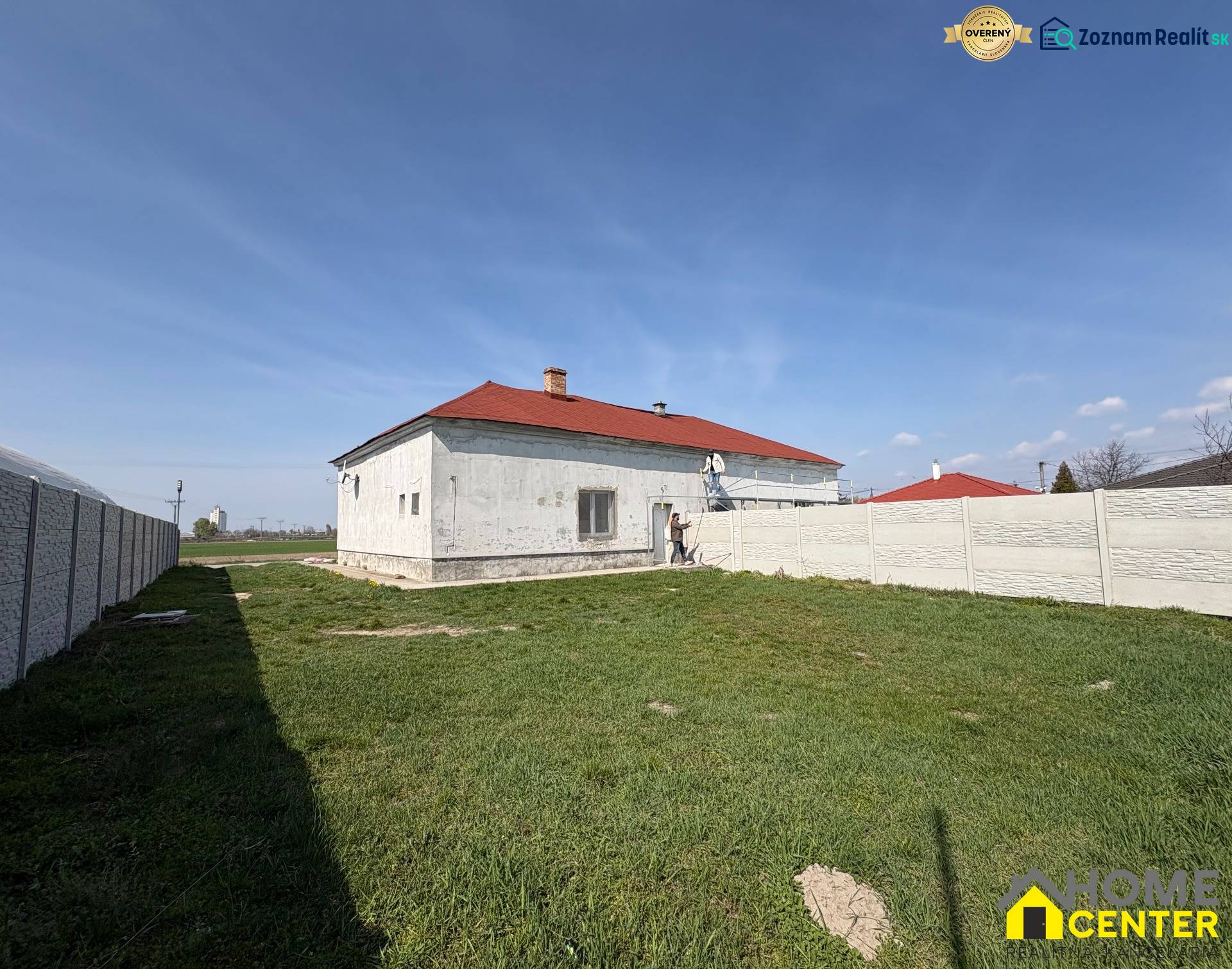 Ein Einfamilienhaus in Zemianska Olča mit weißer Fassade und rotem Dach auf einem grasbewachsenen Grundstück.