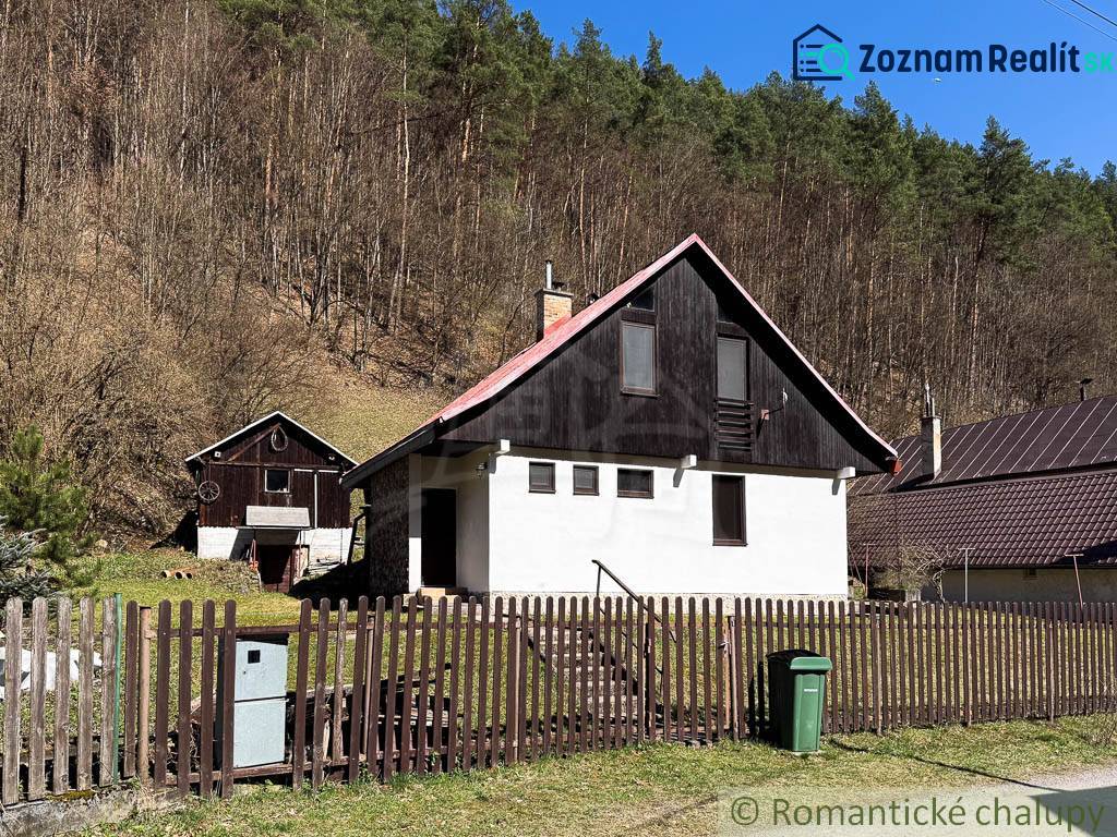 Eine Hütte in Moštenica, umgeben von Wäldern, mit einem Zaun und einem Mülleimer im Hof.