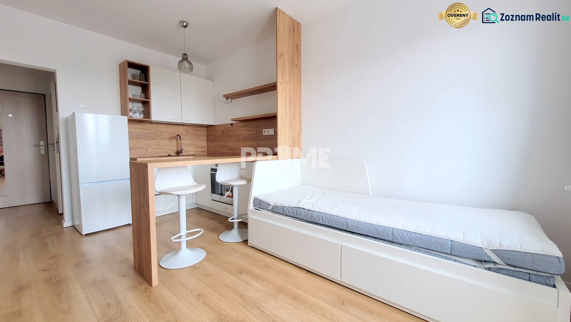 Einzimmerwohnung mit Holzboden, Kochnische, Kühlschrank und Bett.