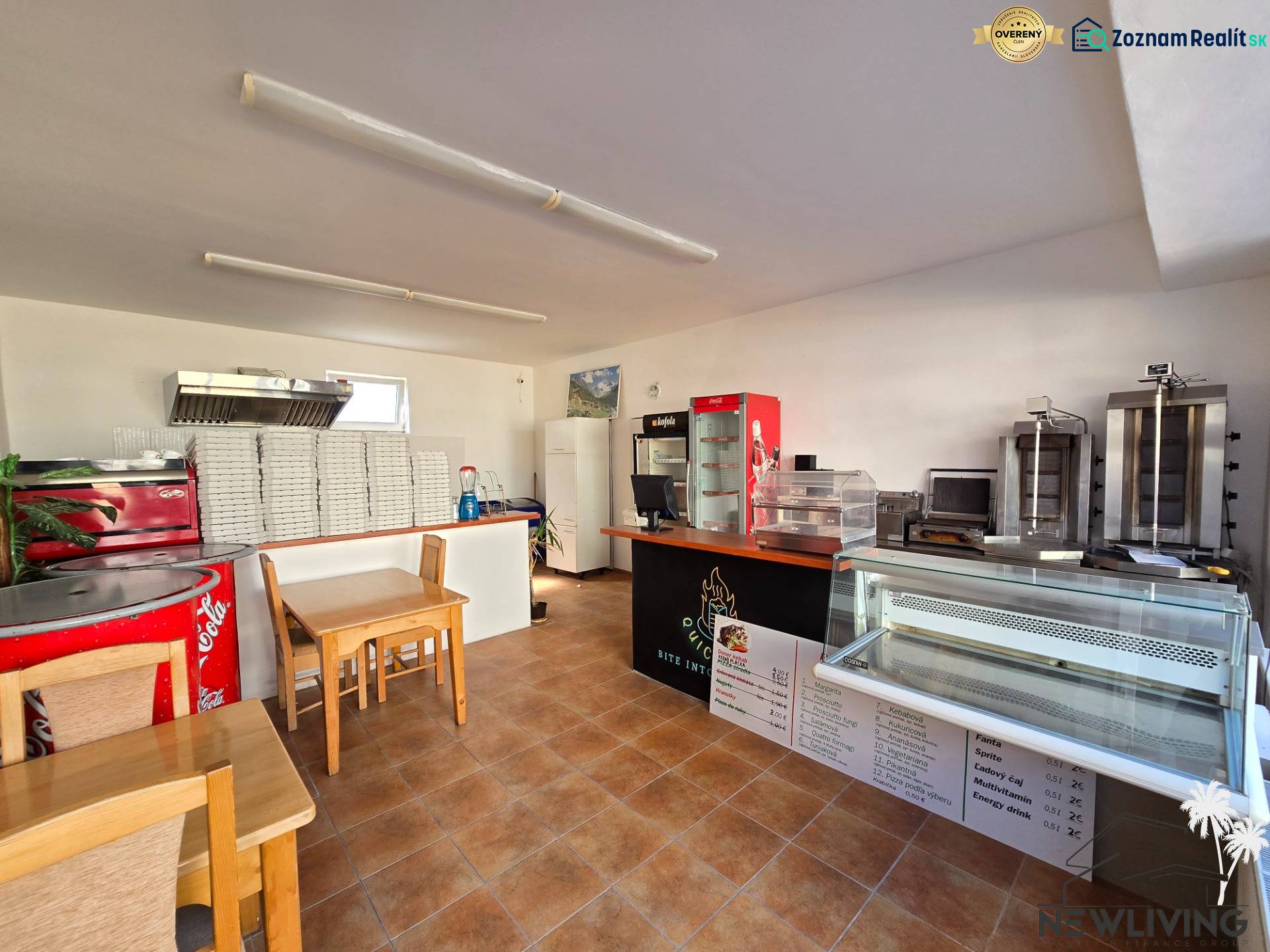 Innenraum eines Gastronomiebereichs mit Tresen, Kühlvitrinen und einem Stapel Pizzakartons.