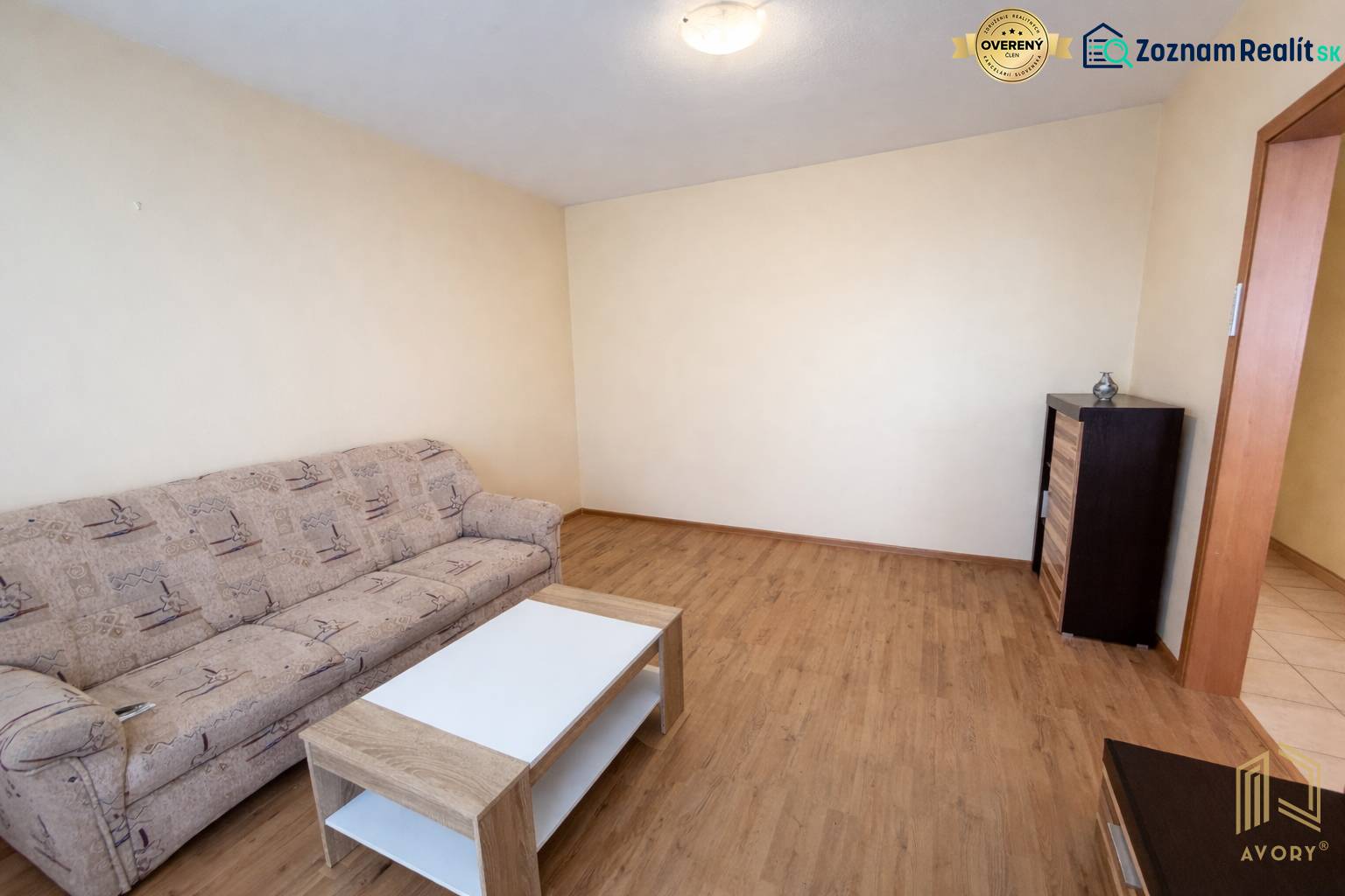 Wohnzimmer mit Sofa, Tisch und Holzboden in einer 2-Zimmer-Wohnung.