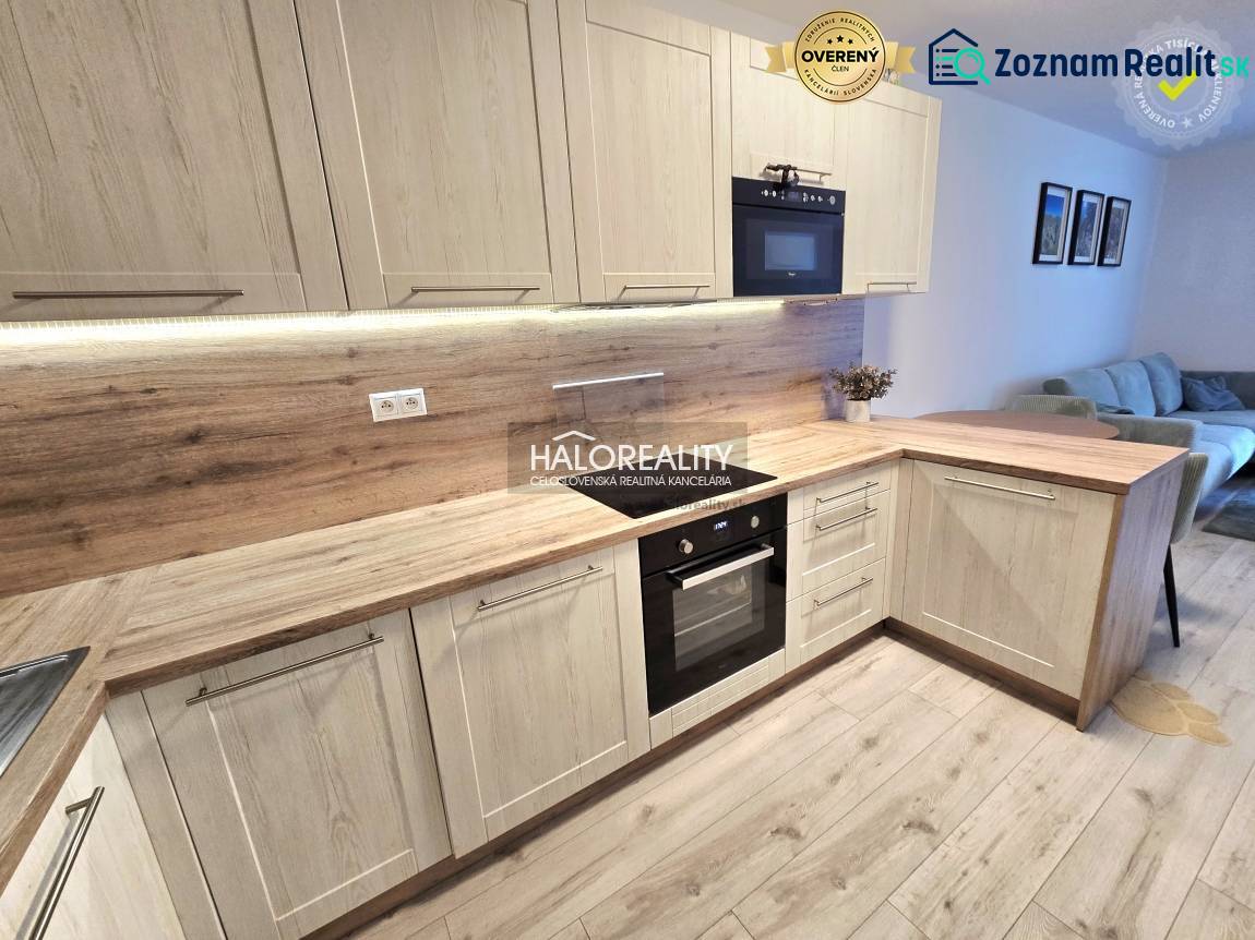 Küche mit Holzboden in einer 2-Zimmer-Wohnung, helle Holzschränke und eingebaute Geräte.