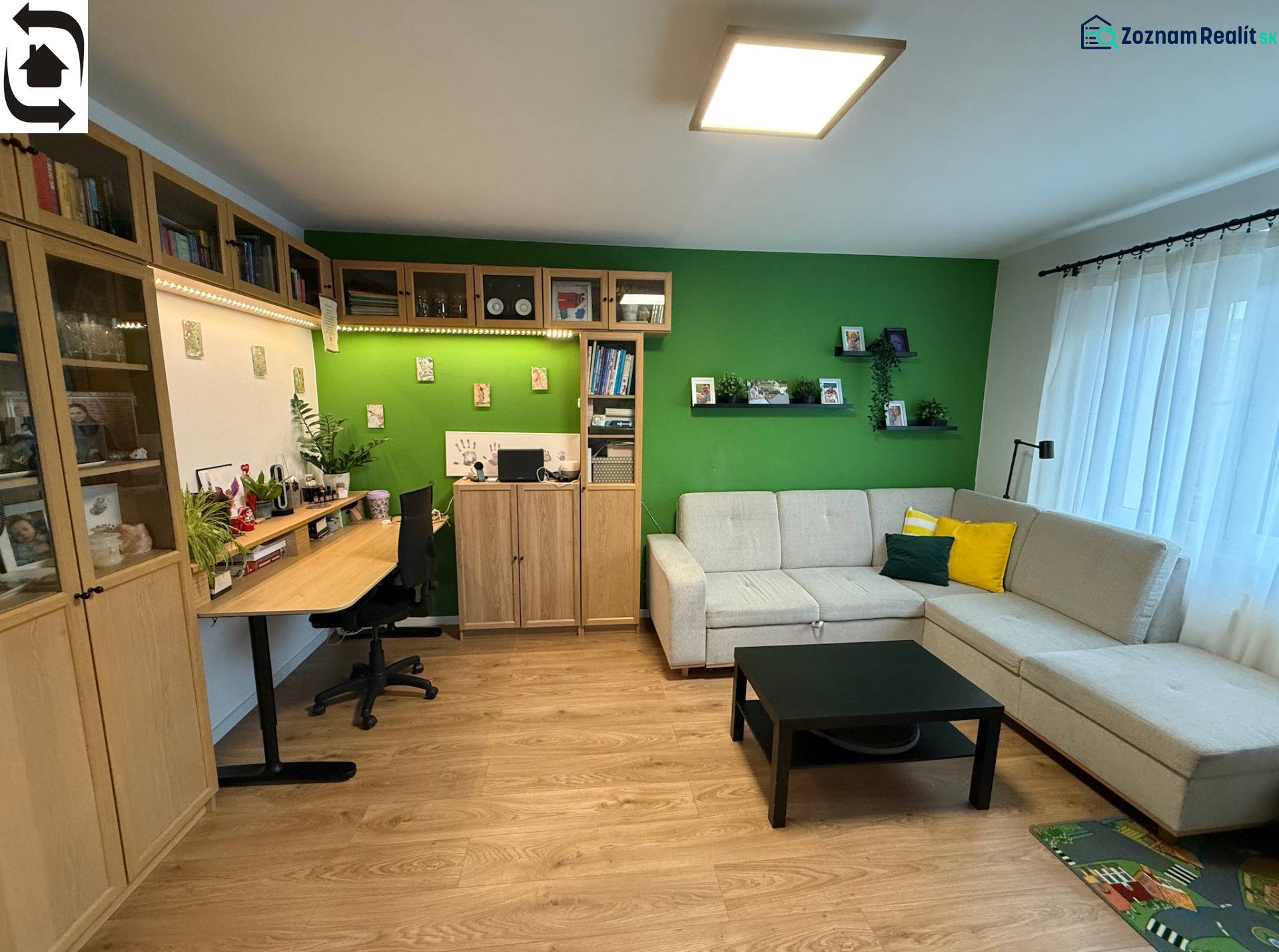 Wohnzimmer mit Sofa, Schreibtisch und Holzboden in einer Vierzimmerwohnung.