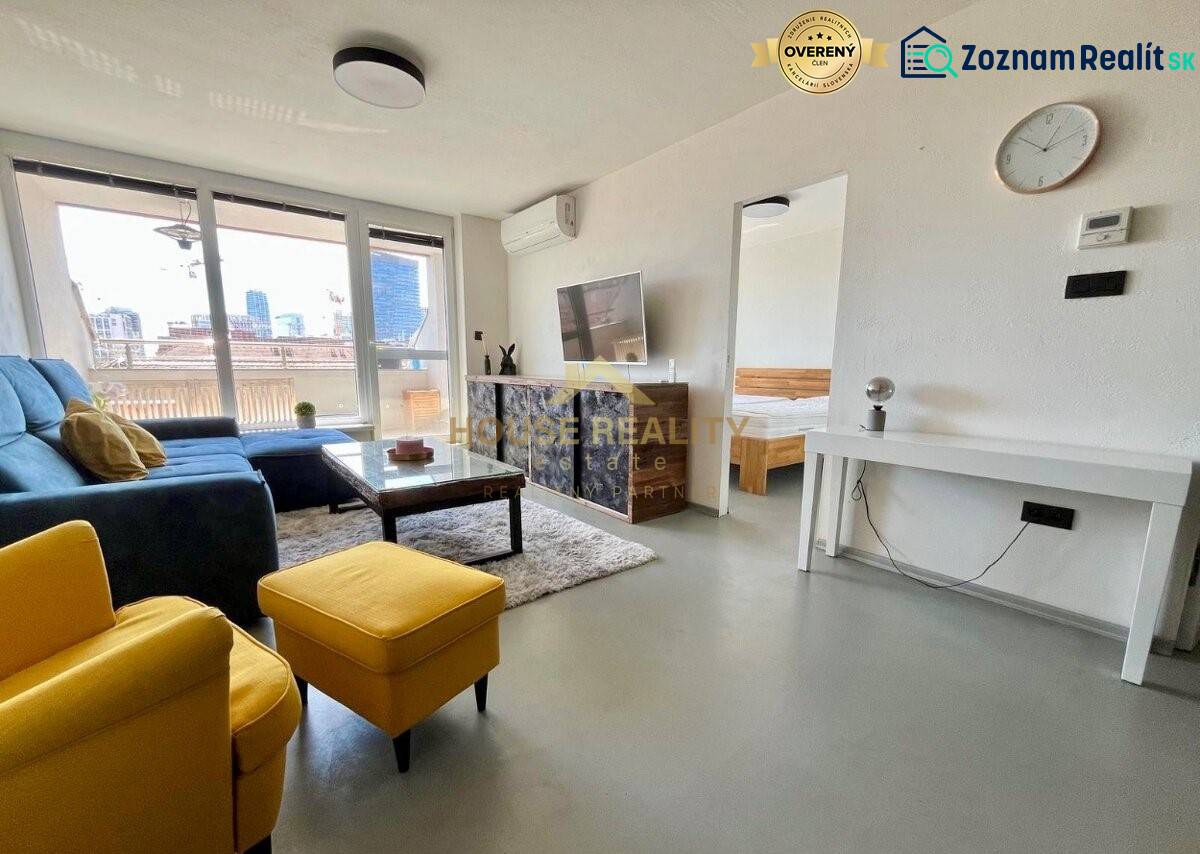 Wohnzimmer einer 3-Zimmer-Wohnung mit Sofa, Fernseher und Balkon.