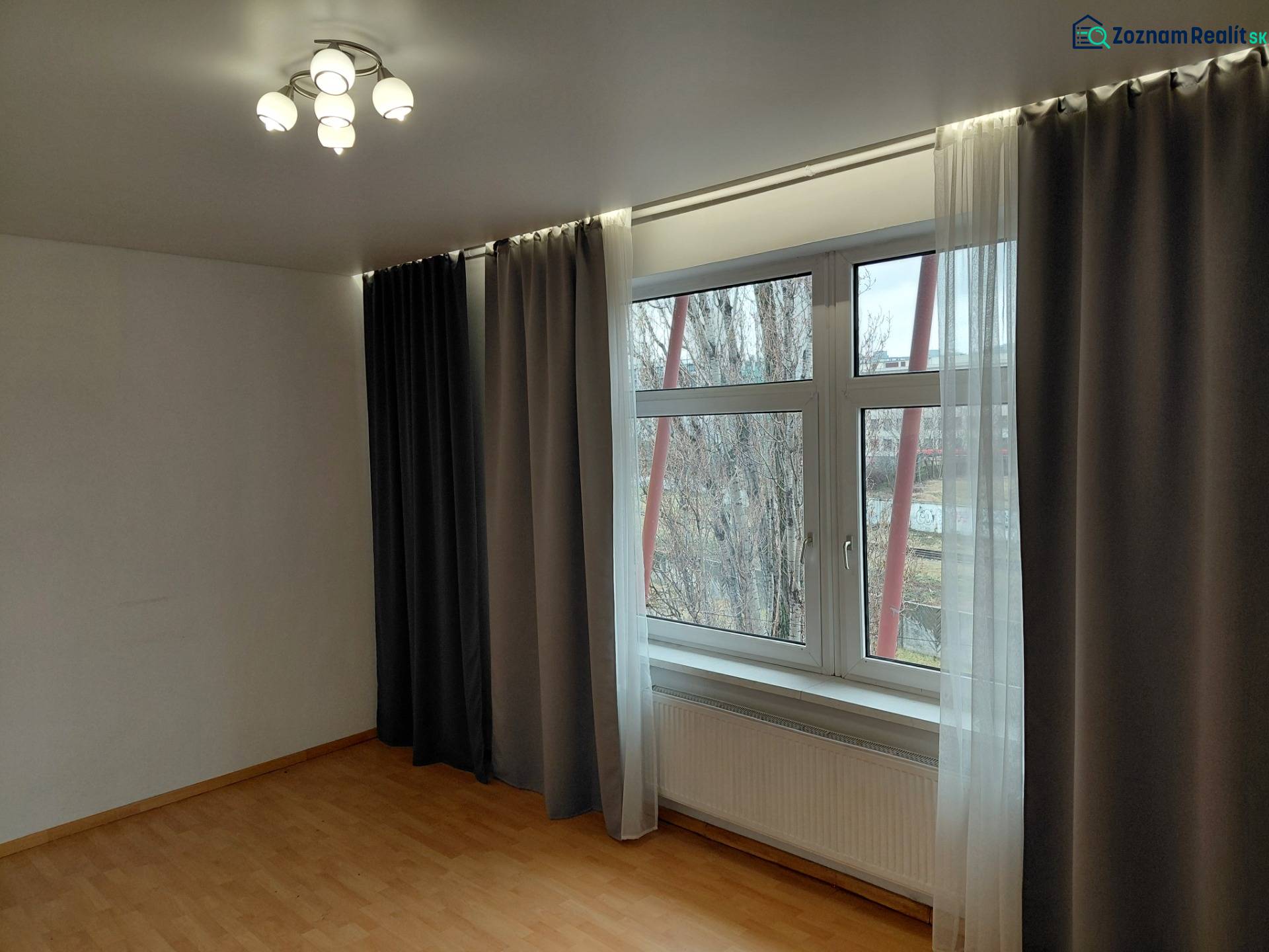 Ein Zimmer mit einem großen Fenster, Verdunkelungsvorhängen und einem Boden mit Holzdekor. Geschäftsräume.