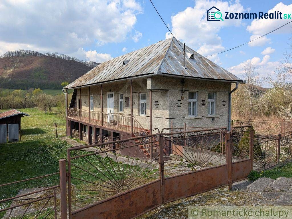 Ein Einfamilienhaus in Zubné mit einem Blechdach, einem Zaun und einer ländlichen Umgebung.