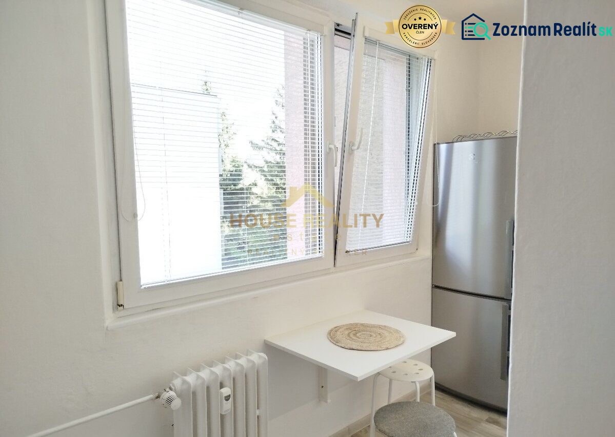 Küchenecke in einer Einzimmerwohnung mit Fenster, kleinem Tisch und Kühlschrank.