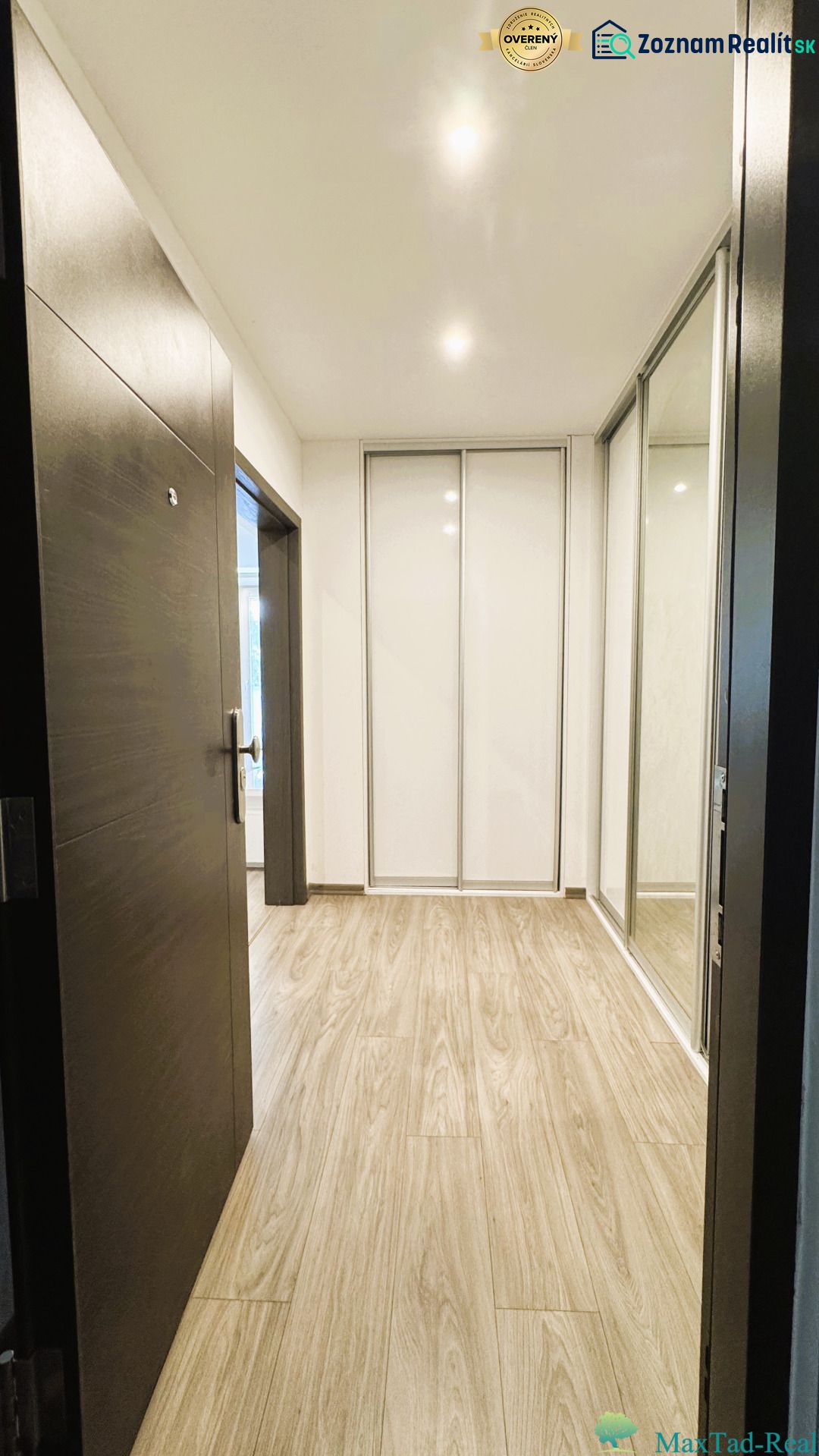 Ein Flur mit einem Spiegelschrank und einem Boden mit Holzdekor in einer 4-Zimmer-Wohnung.