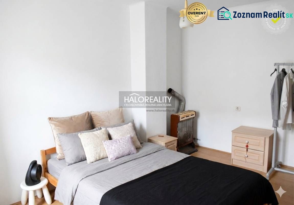 Ein Schlafzimmer in einem Einfamilienhaus mit einem bequemen Bett, einer Kommode und einem Kleiderständer.