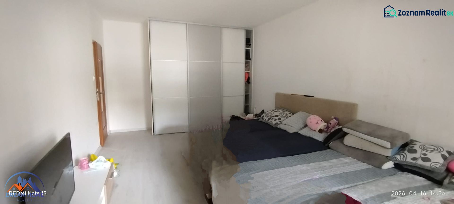 Schlafzimmer in einer 2-Zimmer-Wohnung mit Schiebetürenschrank und Bett, Boden mit Holzdekor.