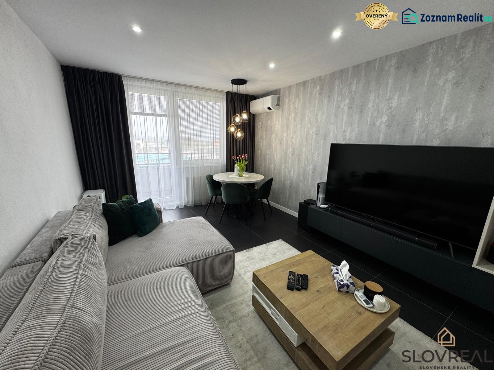 Wohnzimmer einer 3-Zimmer-Wohnung mit Ecksofa und großem Fernseher.