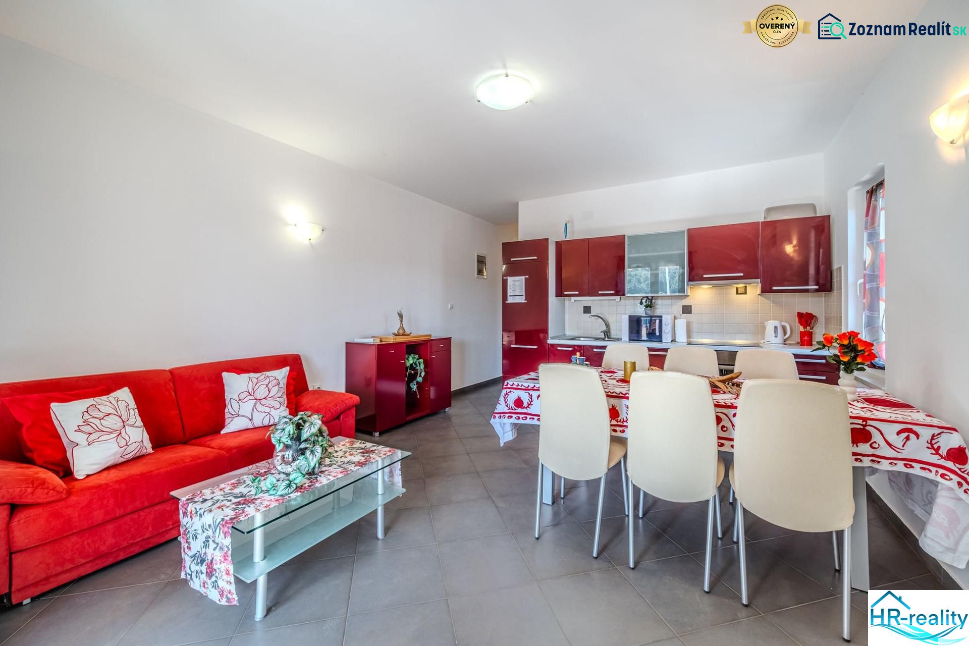 Ferienwohnung mit rotem Sofa und Küche mit Essecke.