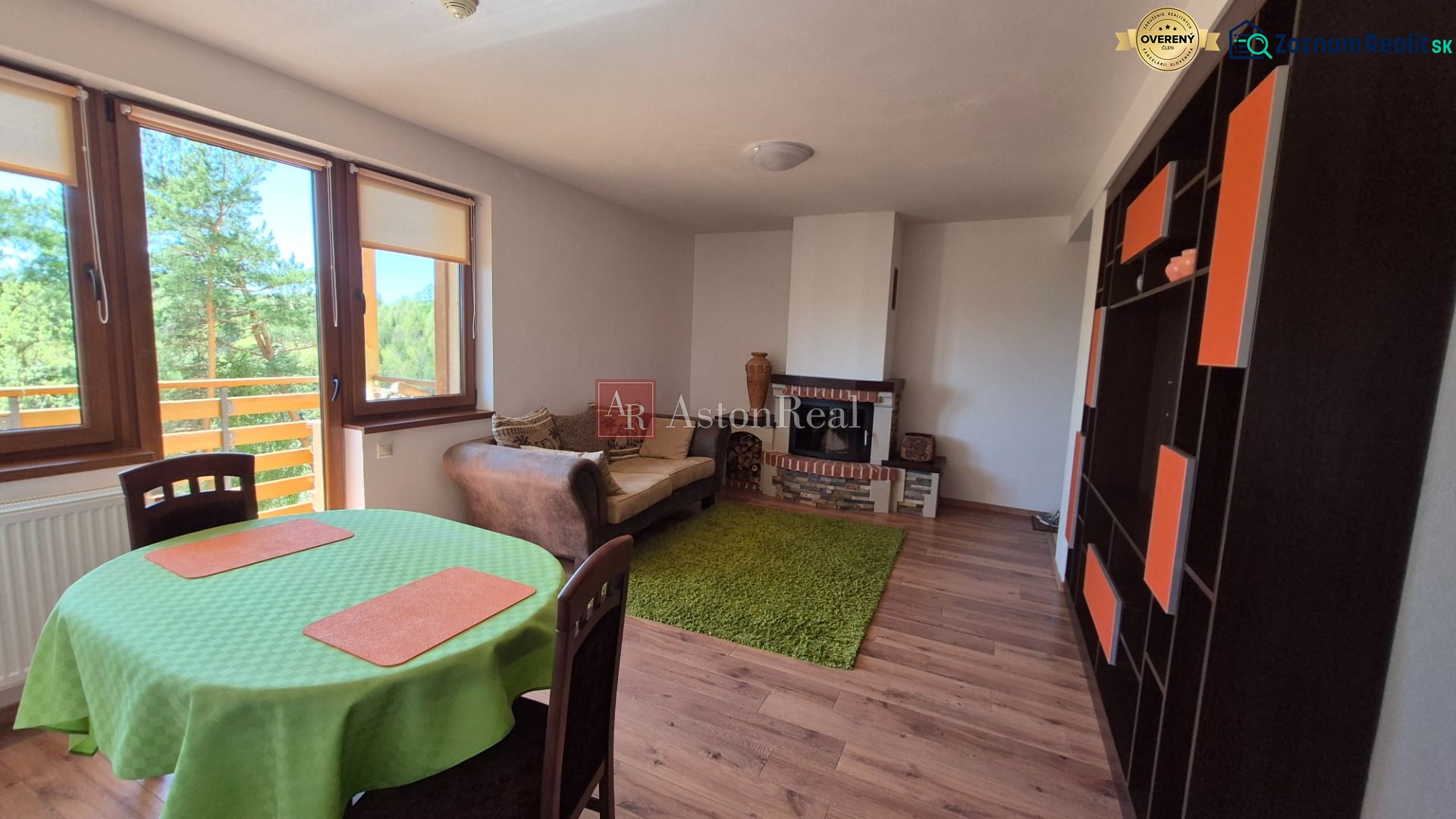 Wohnzimmer in einer Ferienwohnung mit Kamin, Sofa und Blick durch große Fenster.