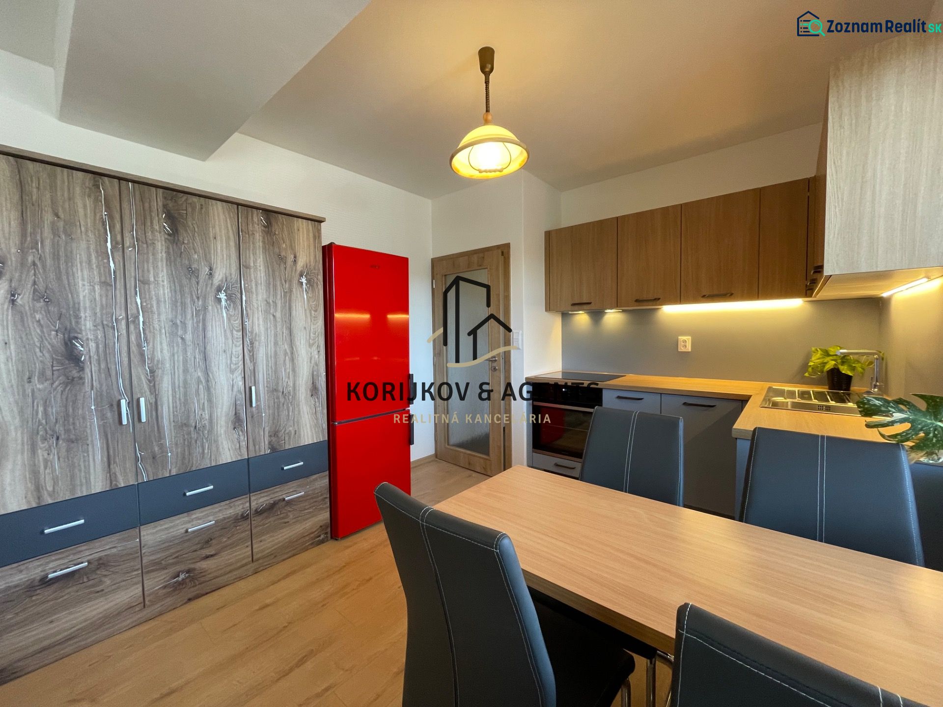 Küche in einer 2-Zimmer-Wohnung mit Schränken in Holzoptik und einem roten Kühlschrank.