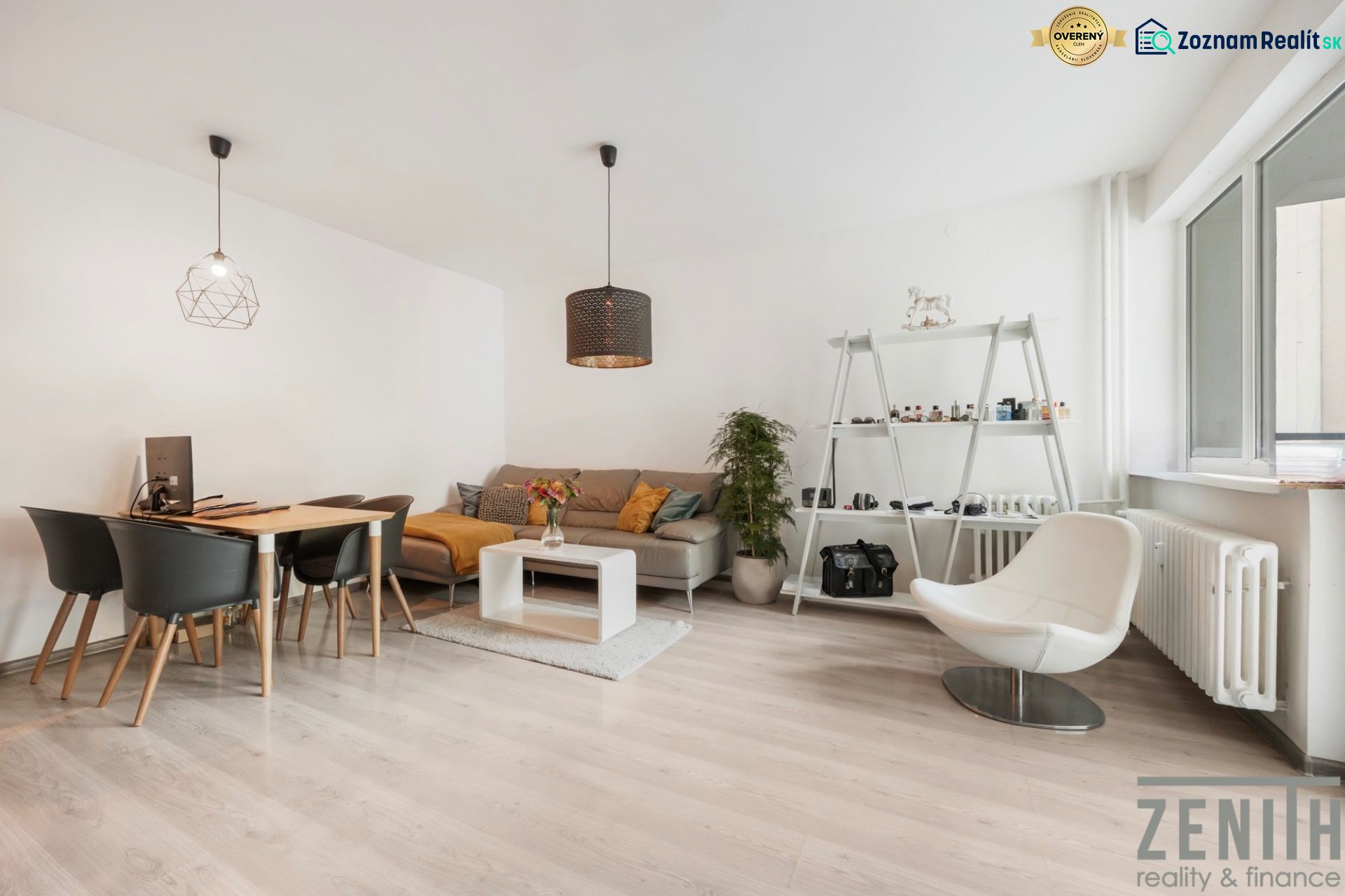 Wohnzimmer in einer Zweizimmerwohnung mit hellem Boden in Holzoptik, modernen Möbeln und Dekorationen.