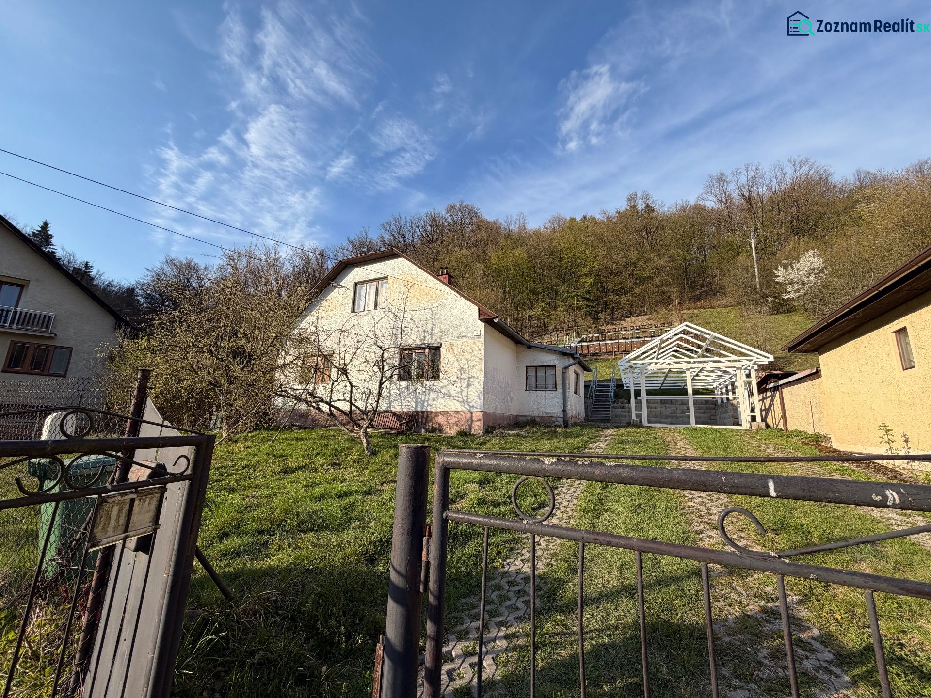 Ein Einfamilienhaus in Štós mit einem Unterstand im Hof, grünem Rasen, umgeben von Natur.