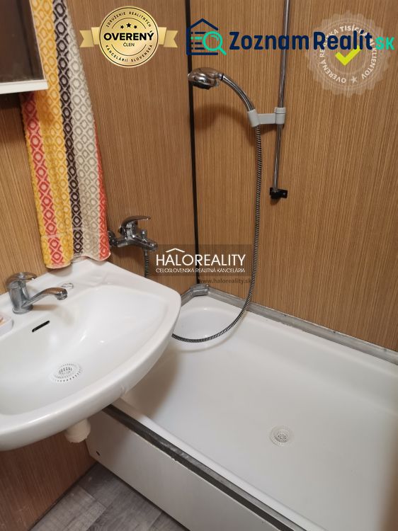 Badezimmer in einem Studio-Apartment mit Badewanne und Waschbecken, Boden mit Holzdekor.
