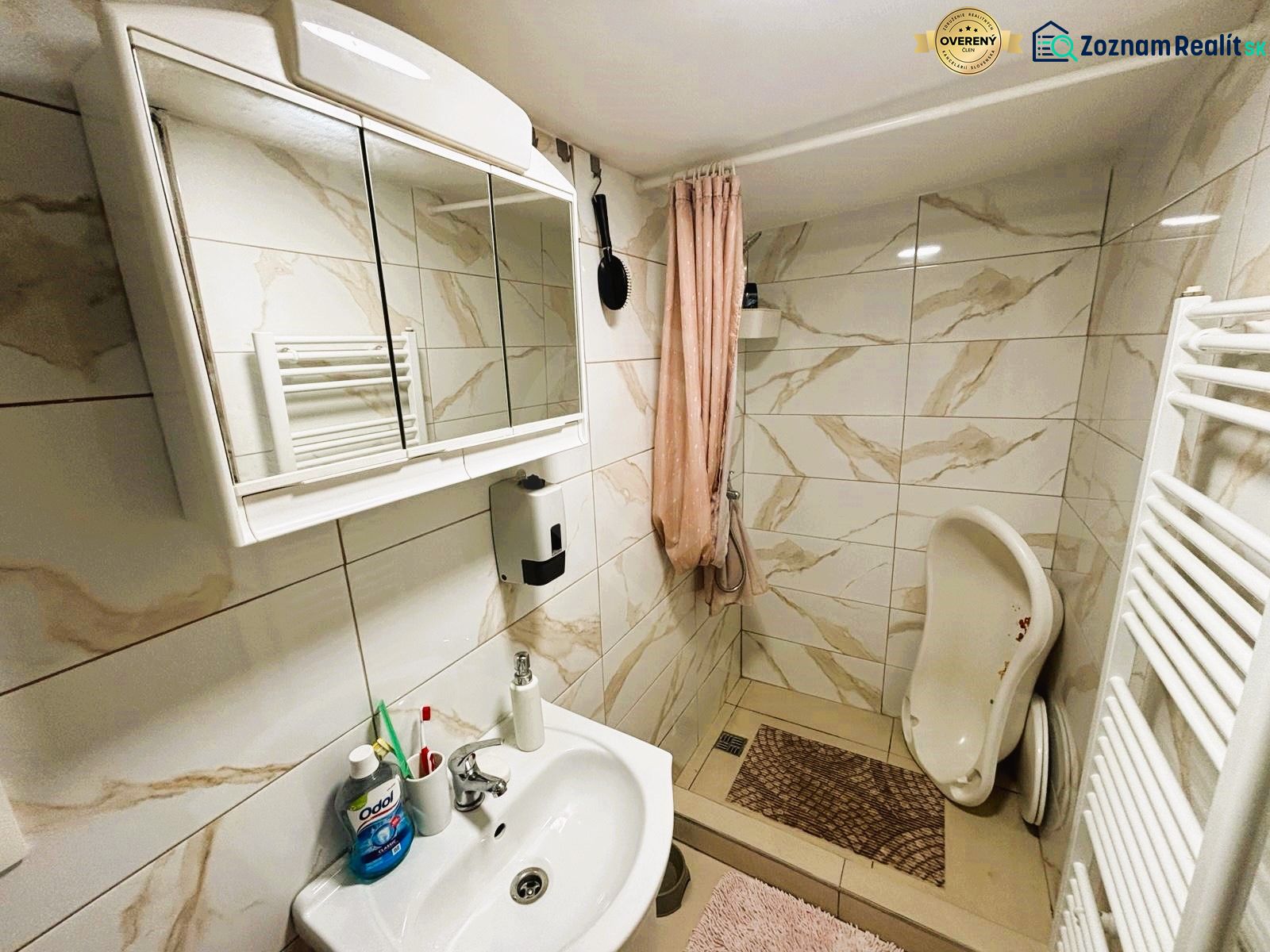 Ein Badezimmer in einer Hütte mit einem weißen Waschbecken, einem Spiegelschrank und einer Duschkabine.