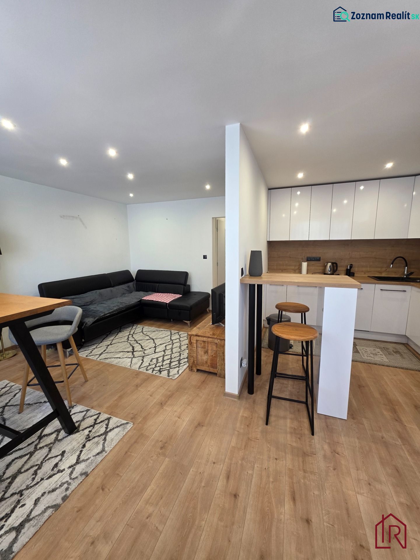 Wohnzimmer mit Küche in einer 3-Zimmer-Wohnung, Boden mit Holzdekor, Sitzgarnitur.