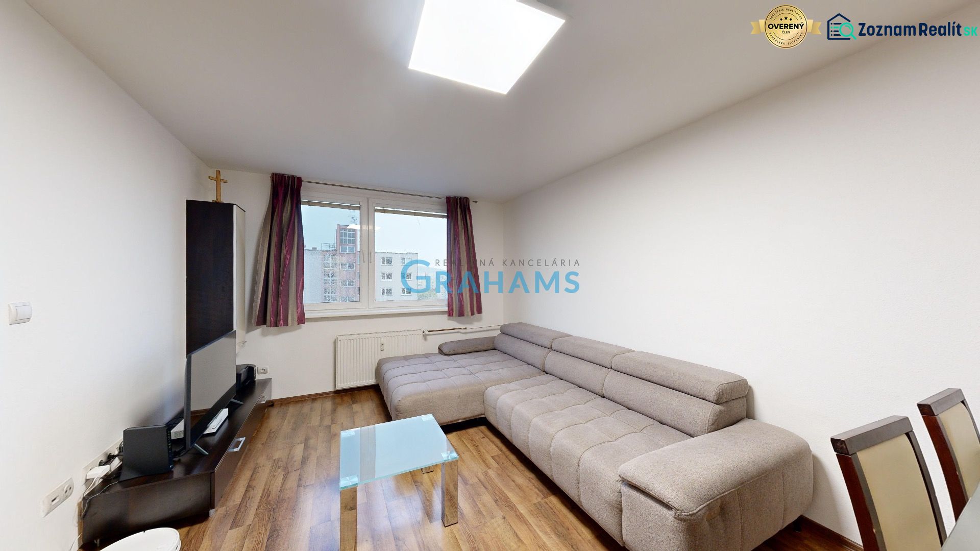 Wohnzimmer mit grauem Sofa und Holzboden in einer 3-Zimmer-Wohnung.