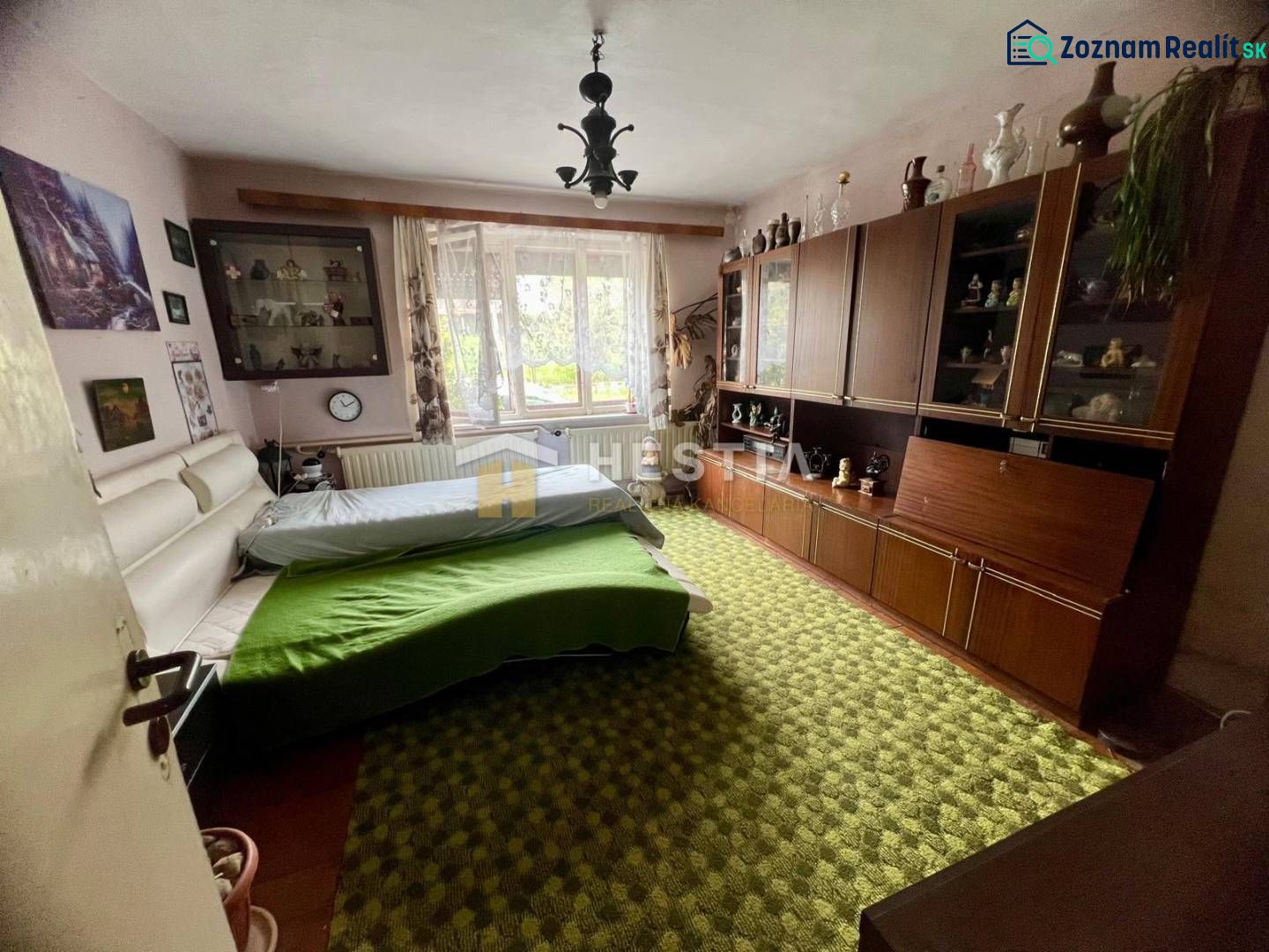 Schlafzimmer in einem Einfamilienhaus mit Teppichboden, Schrankwand und großem Fenster.