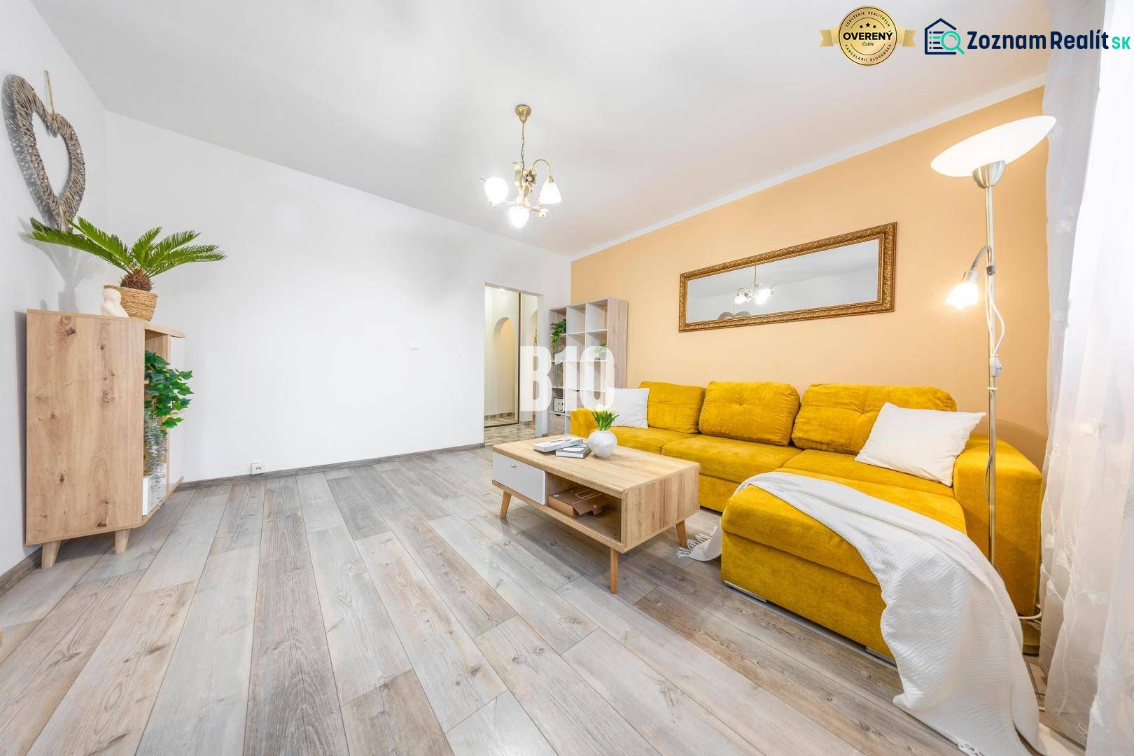 Wohnzimmer in einer 2-Zimmer-Wohnung mit Holzboden und gelbem Sofa.