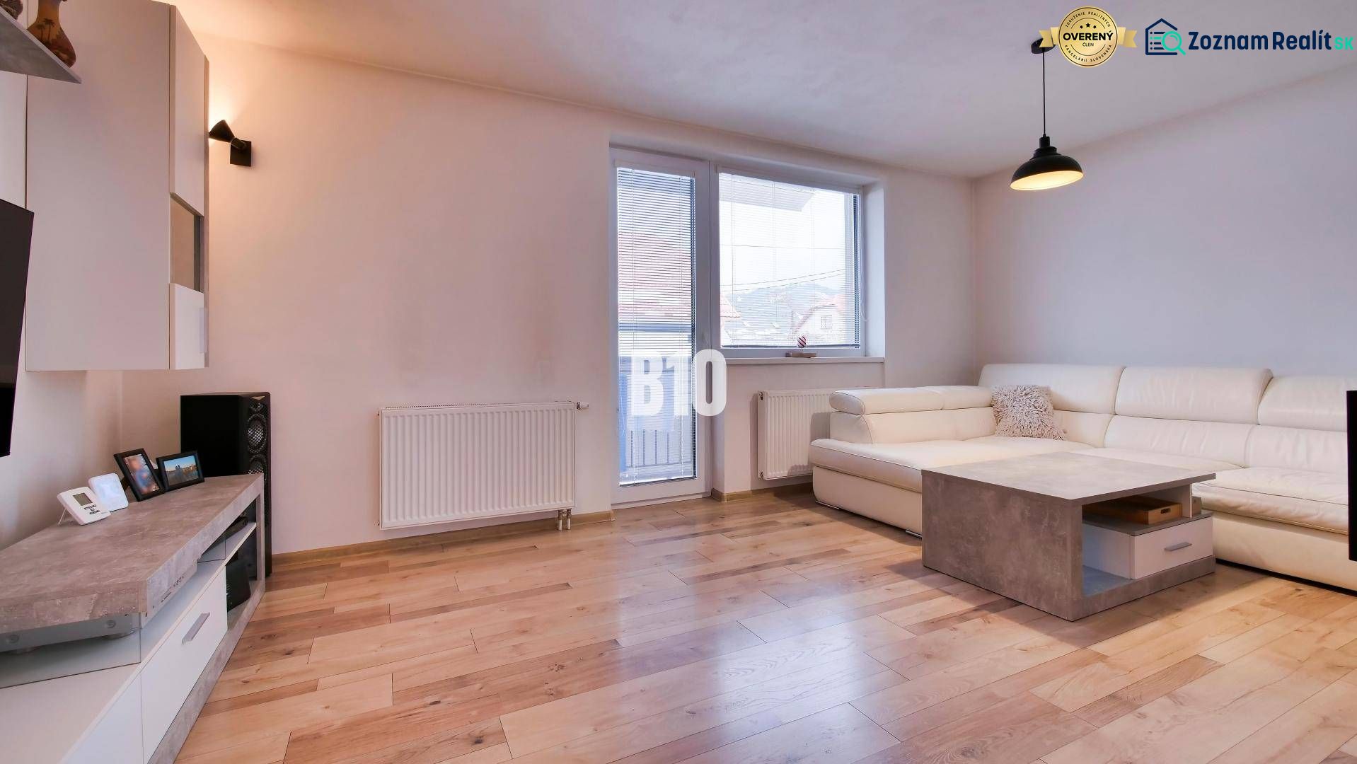 Wohnzimmer in einer 3-Zimmer-Wohnung mit Holzboden und weißem Sofa.