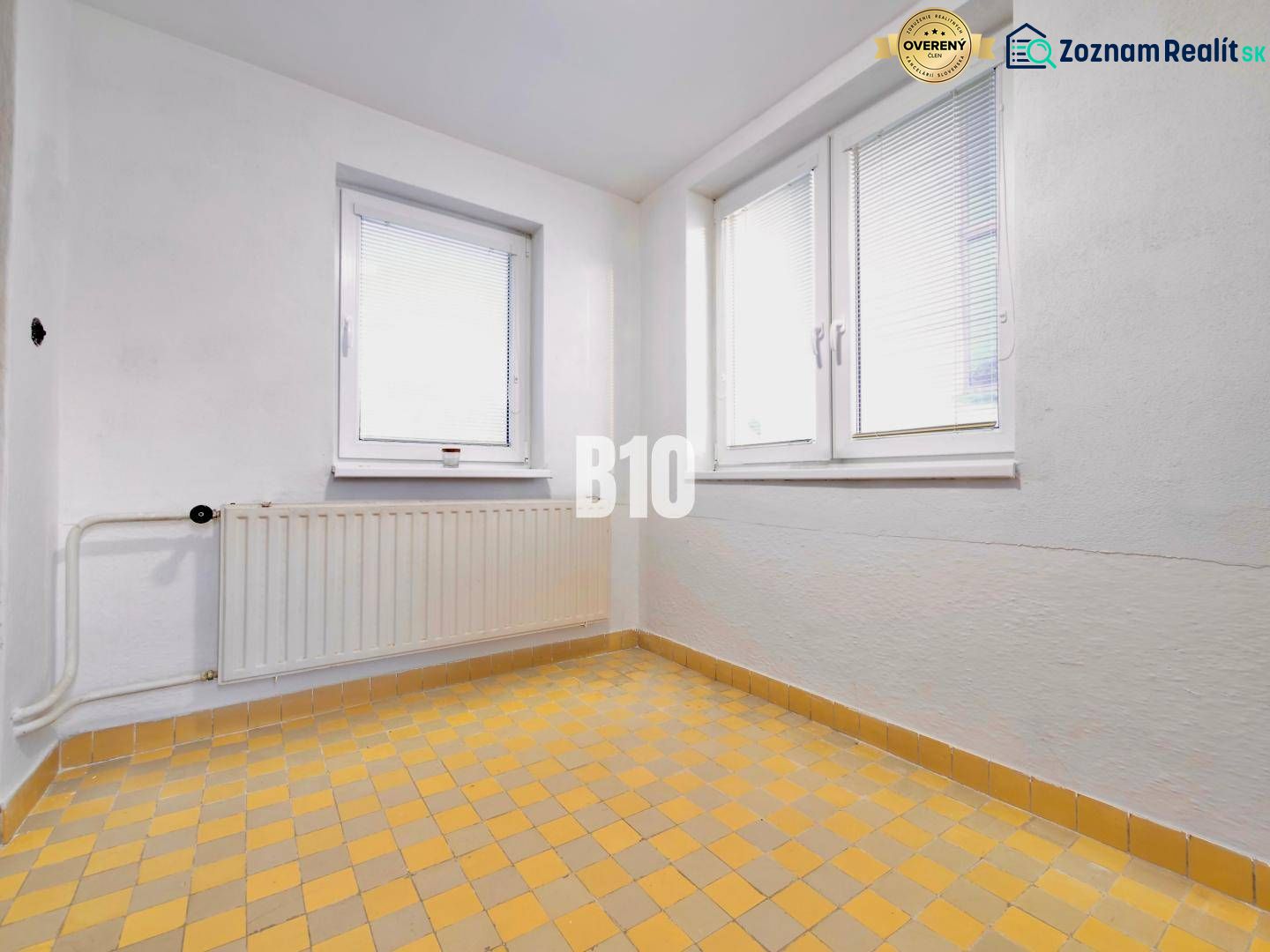 Weiße Wand, Fenster, Heizkörper und gelber Fliesenboden in einem Einfamilienhaus.