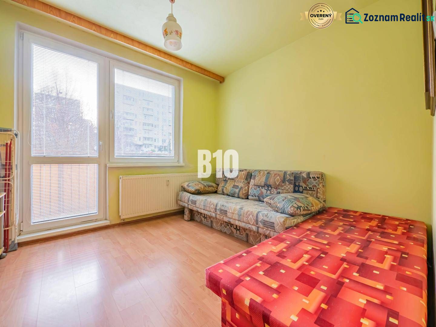 Ein Zimmer in einer 3-Zimmer-Wohnung mit einem Sofa und einem Boden in Holzoptik.