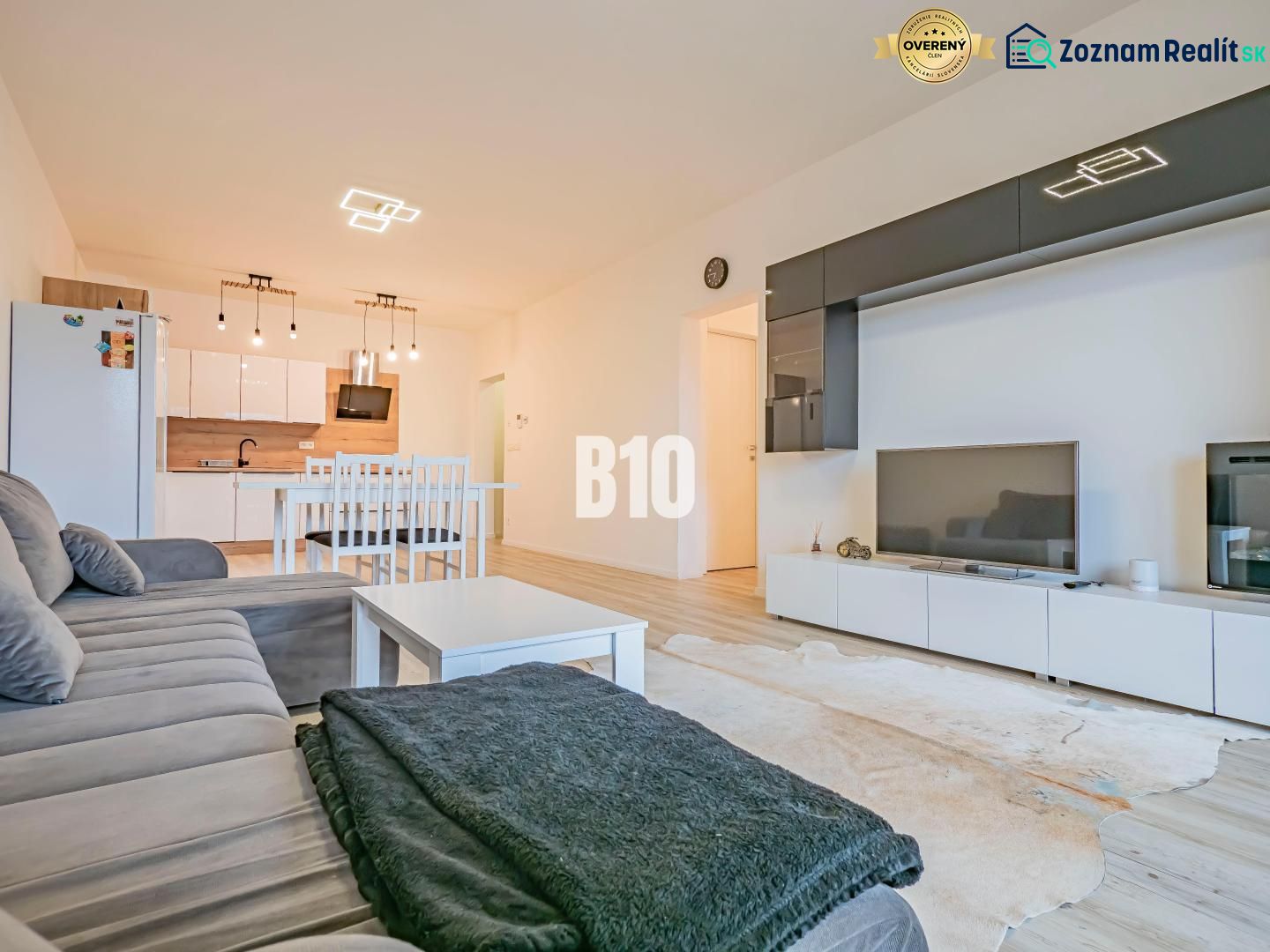 Wohnzimmer mit Küche, weiße Möbel, Sofa und Boden mit Holzdekor.