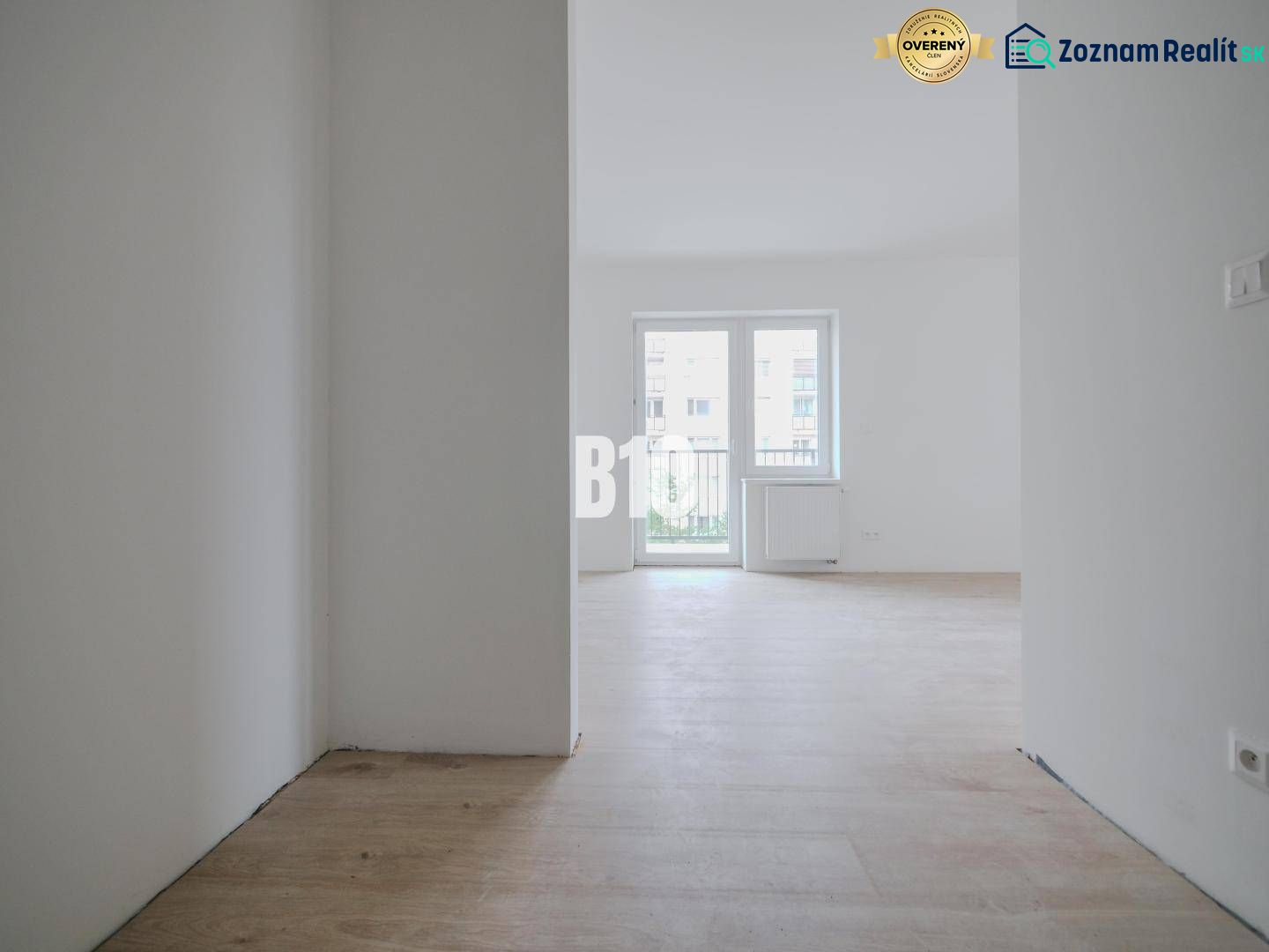 Helles leeres Interieur mit Holzboden und großem Fenster in einem Einzimmerapartment.