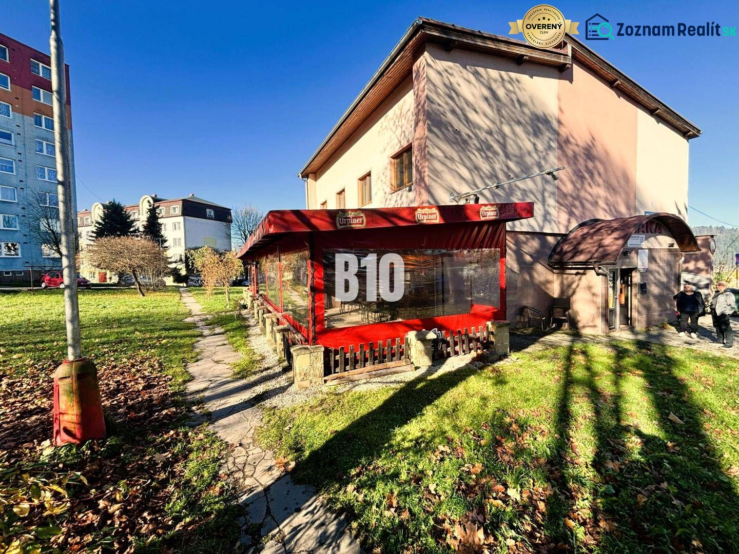 Ein Gebäude in Čadca mit Garten, Terrasse und roter Markise bei sonnigem Wetter.