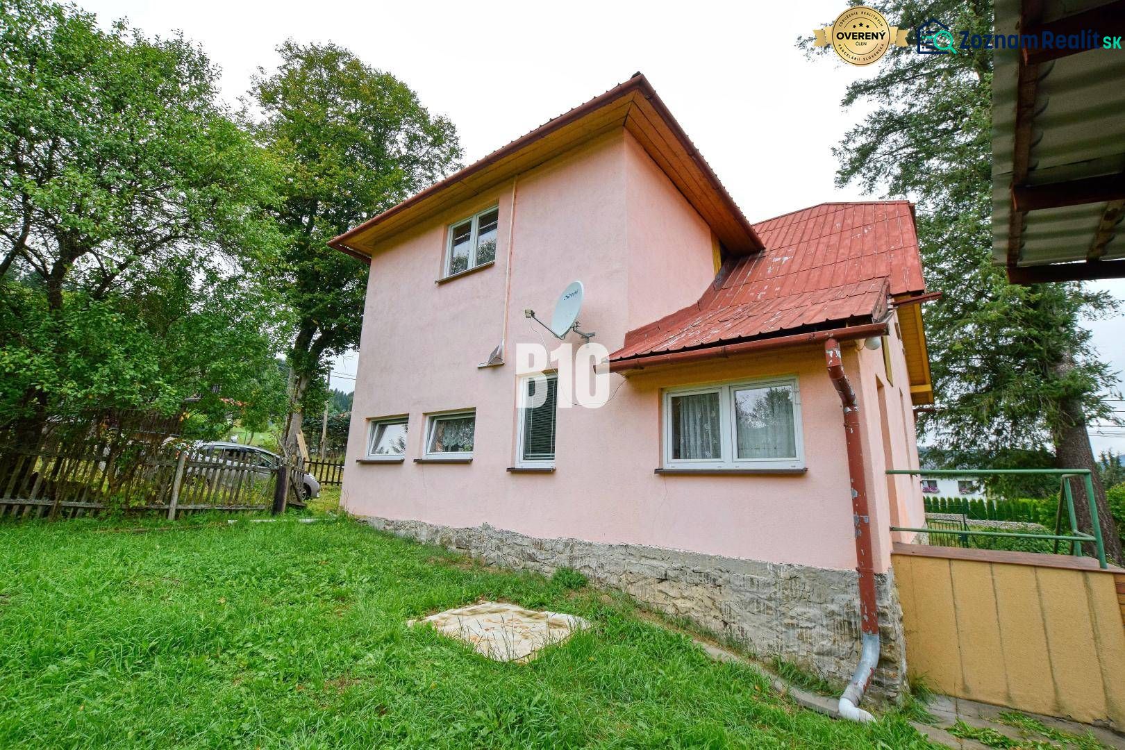 Einfamilienhaus in Makov mit rosa Fassade, Garten und Satellitenschüssel an der Wand.